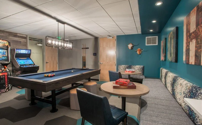 Game room with a pool table, arcade machine, round table with chairs, and wall art.