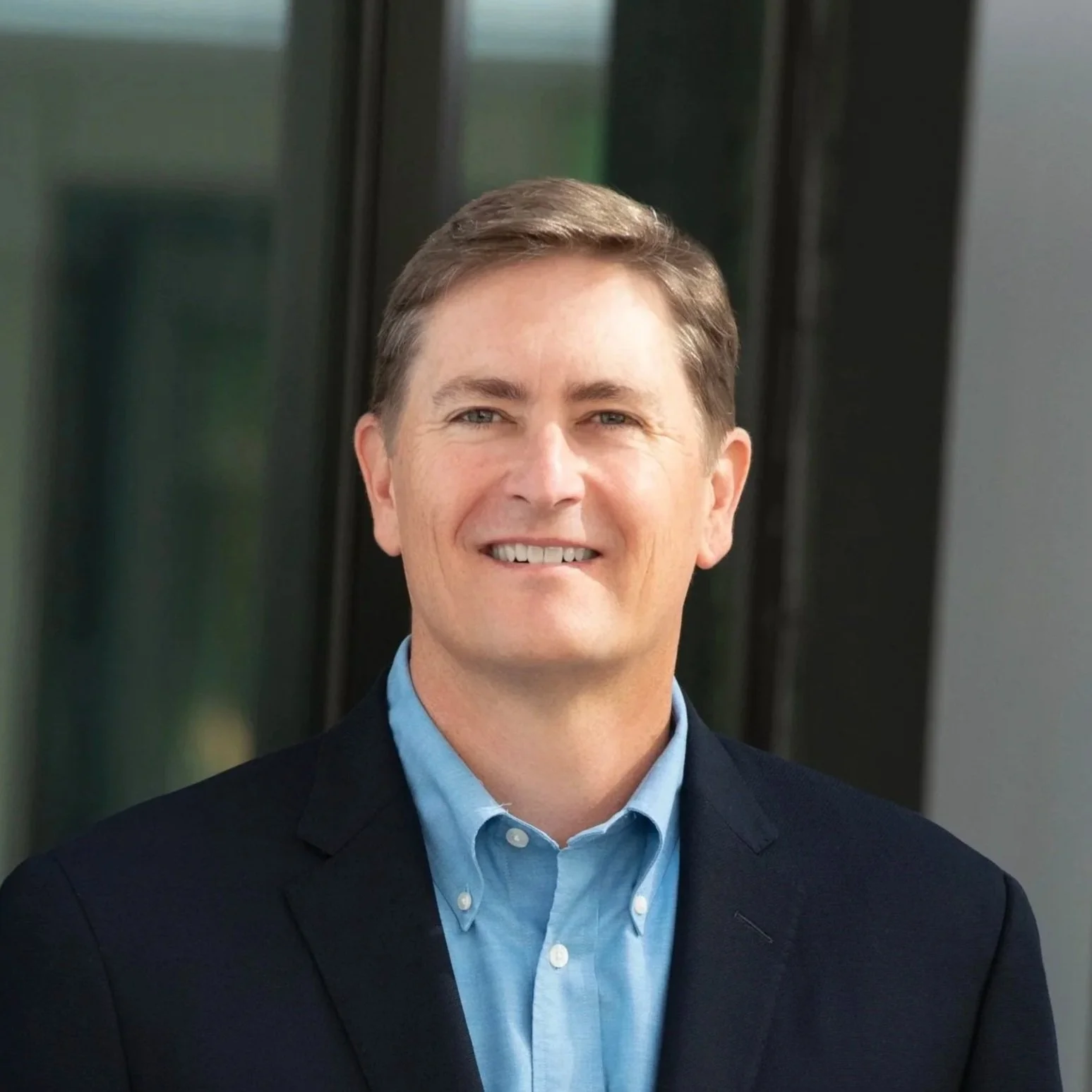 Headshot of a smiling man in business attire outside
