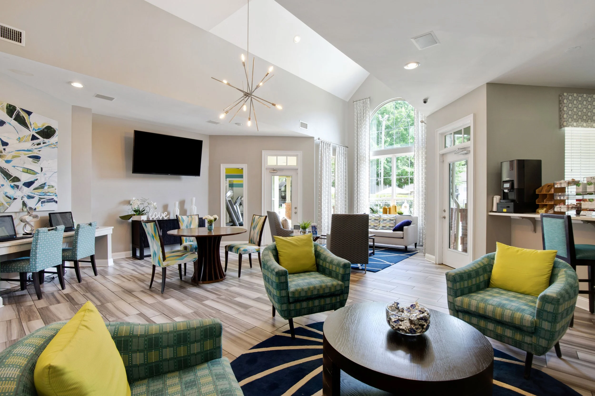 Bright and airy hotel lobby or lounge with large windows, modern furniture, and a high ceiling with a chandelier.