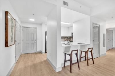 Modern apartment interior with a hallway, kitchen, and bar stools