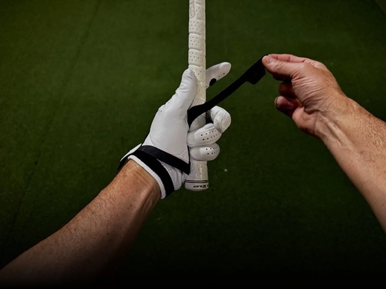 A person wearing the Practice Glove and adjusting it while holding a golf club.