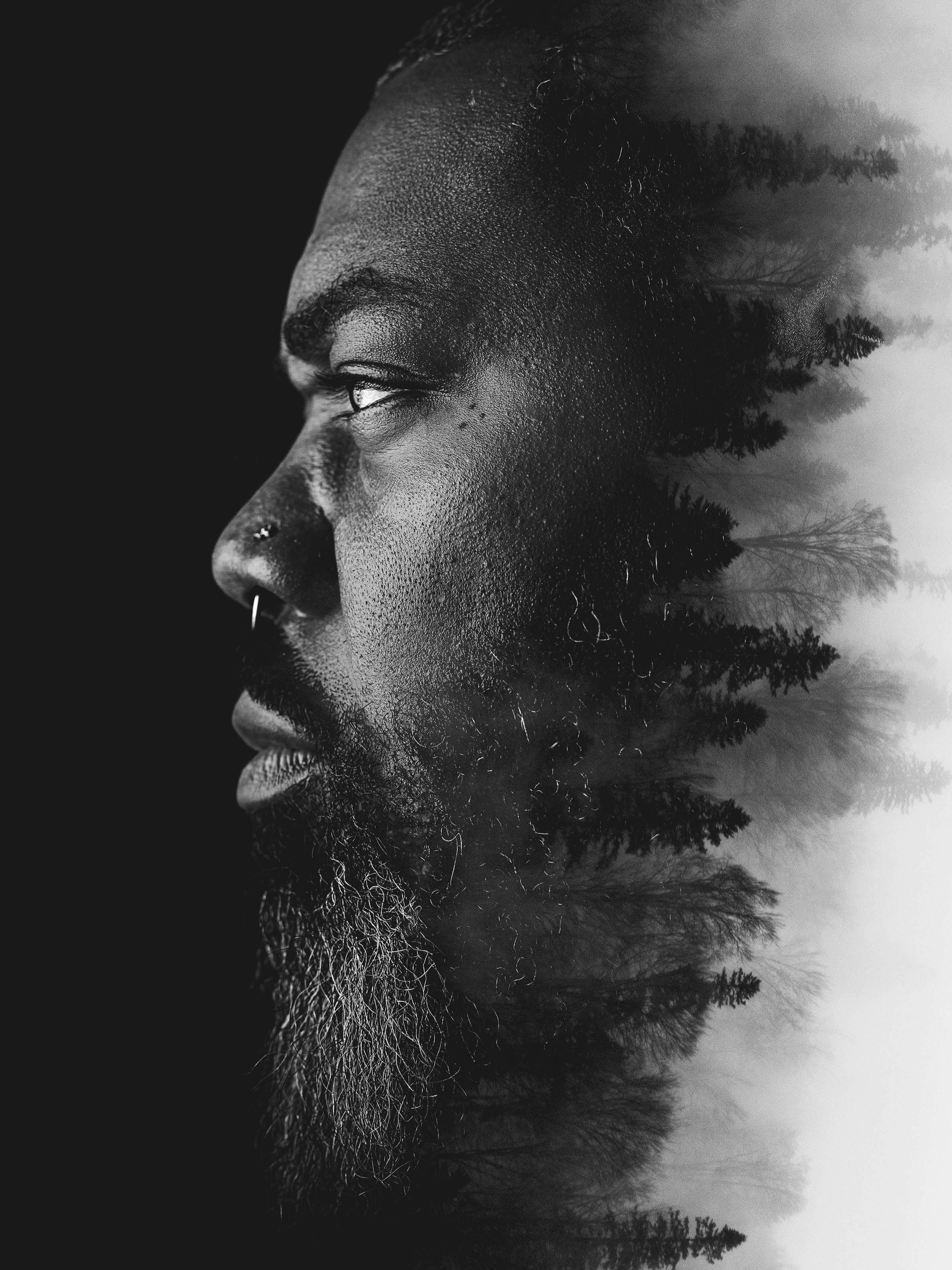 Double exposure portrait blending a bearded man’s profile with forest scenery for conceptual visual storytelling.