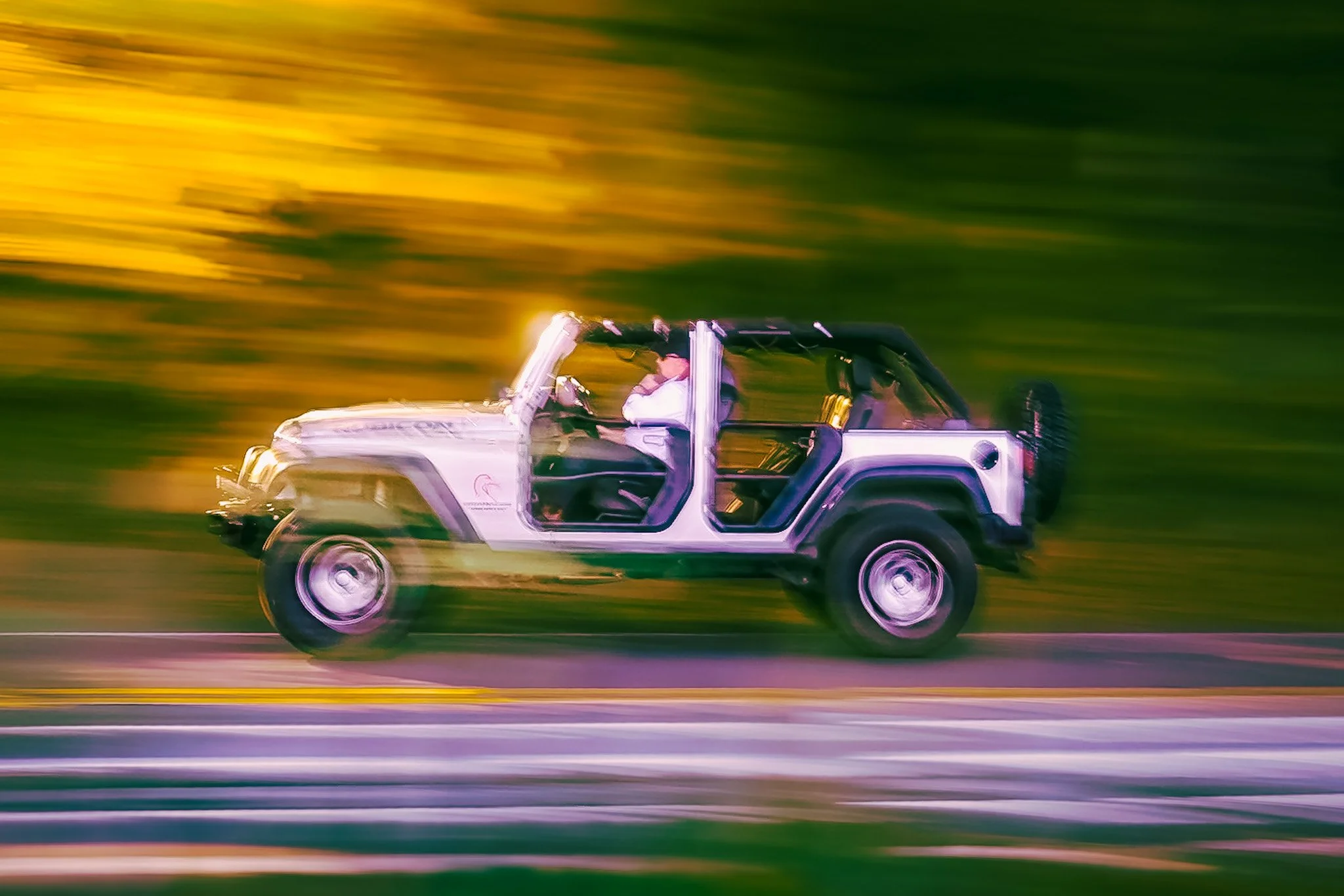 A white off-road vehicle driving at high speed on a road during sunset, with a motion blur effect.