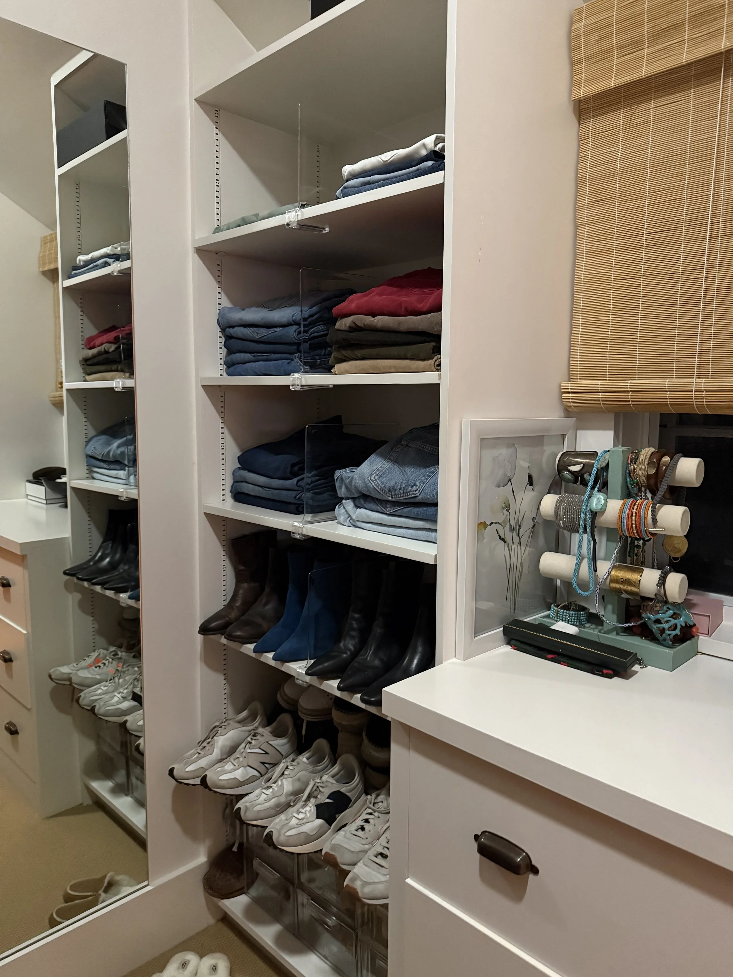 Closet with shelves holding folded clothes, organized shoes, and jewelry on a stand.