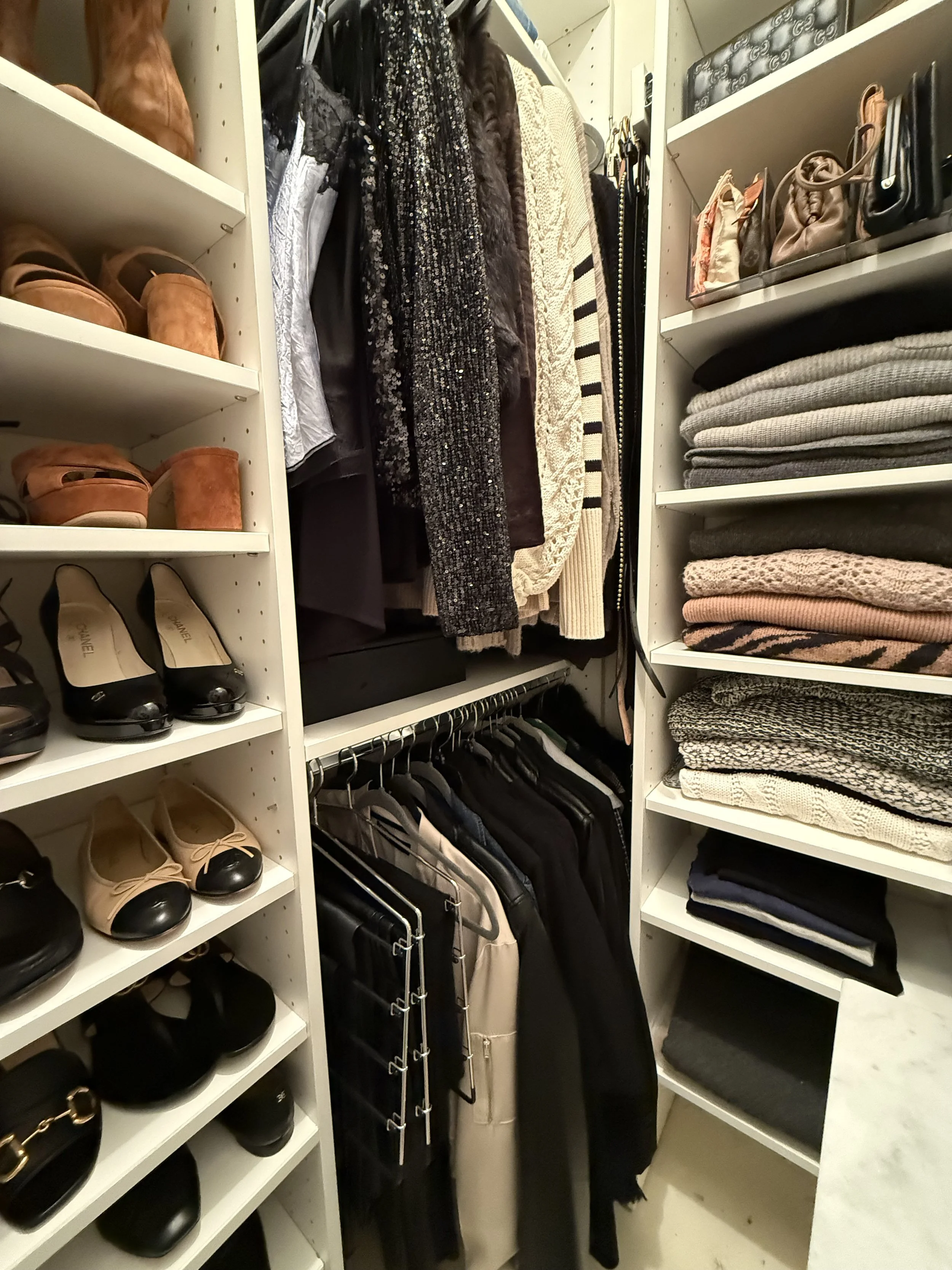 Closet with shelves of shoes, handbags, folded clothes, and hanging garments.