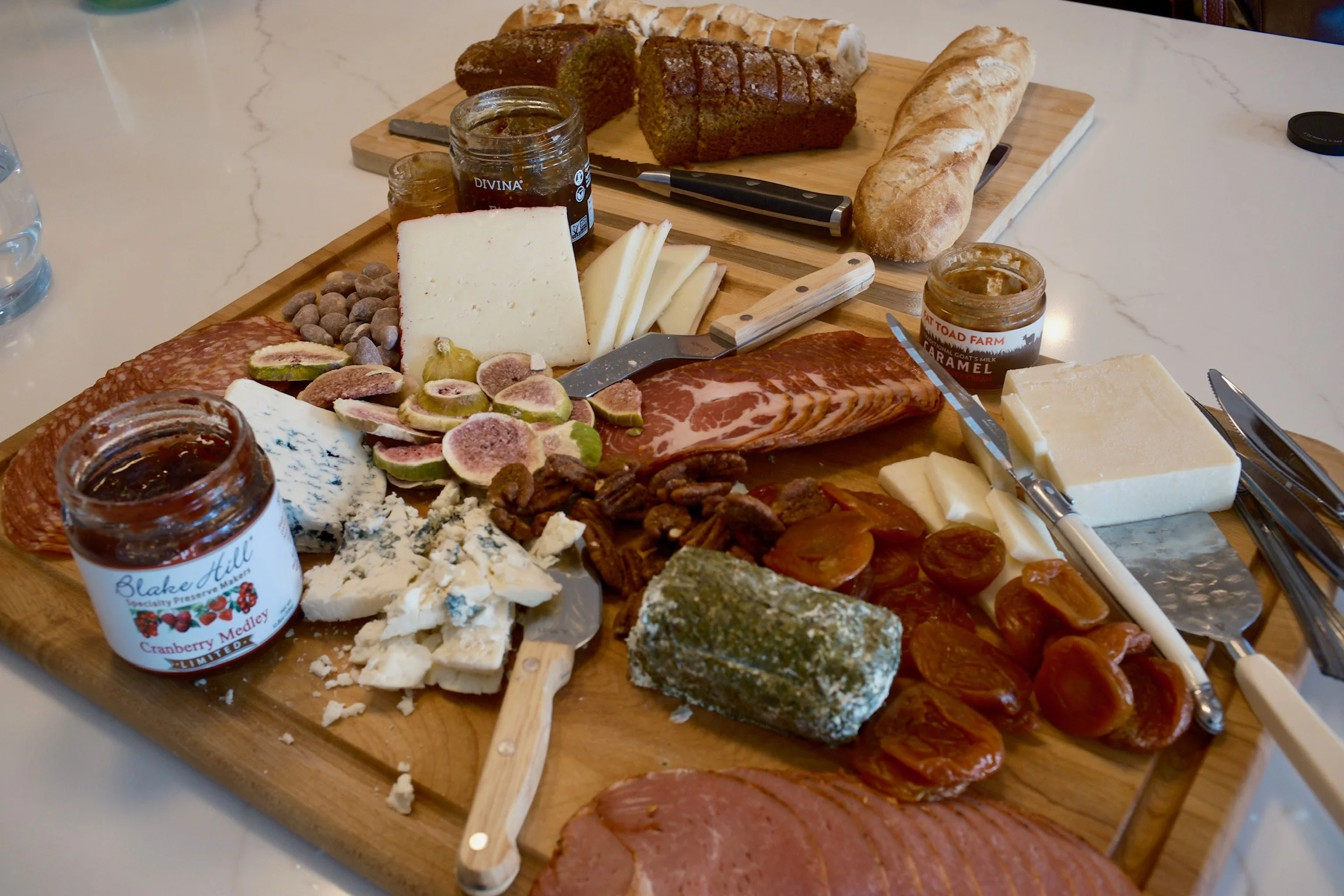 A charcuterie board with assorted cheeses, meats, bread, and spreads on a wooden platter.