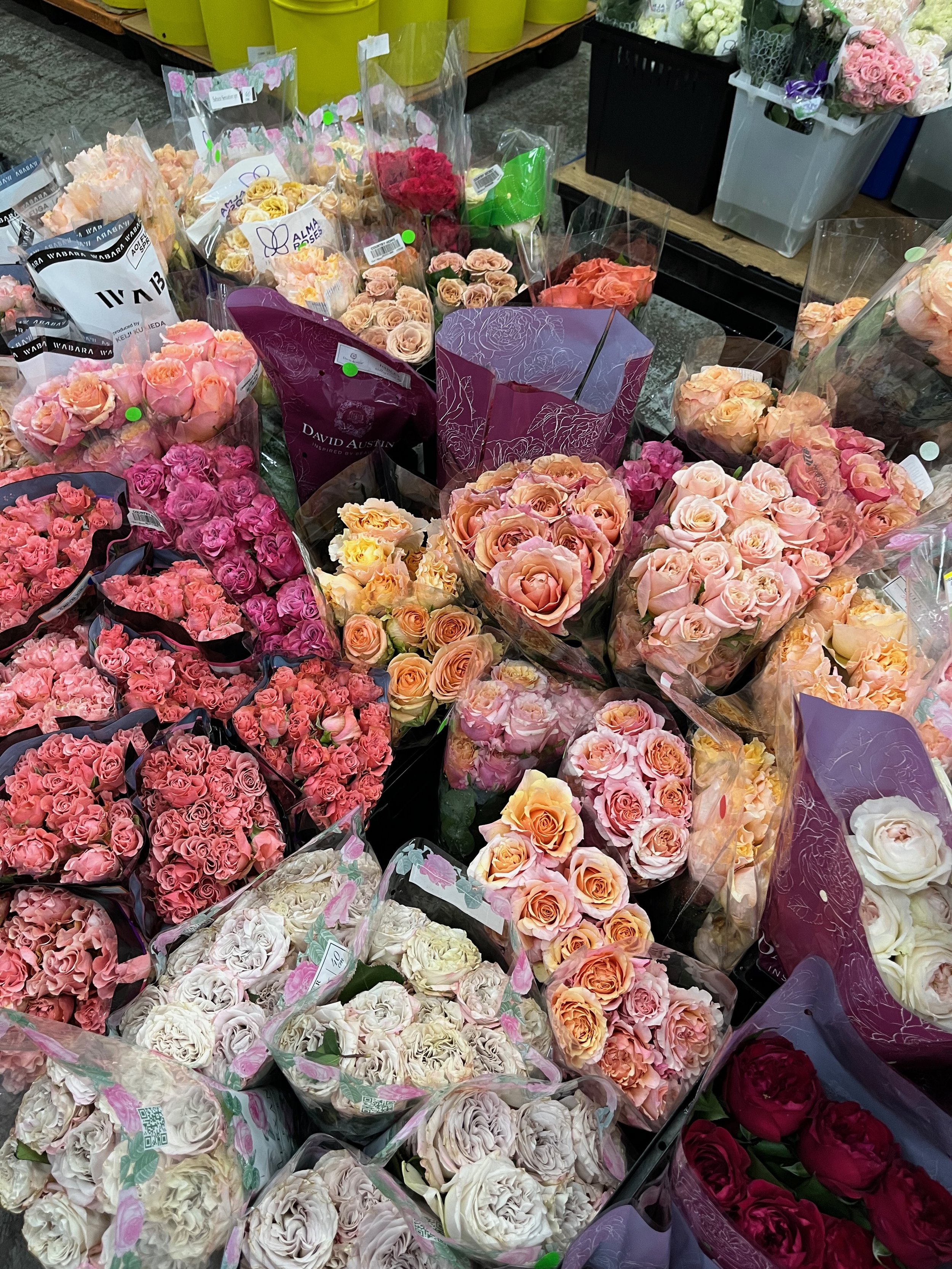 Various bouquets of pink, peach, and white roses on display at a flower shop.