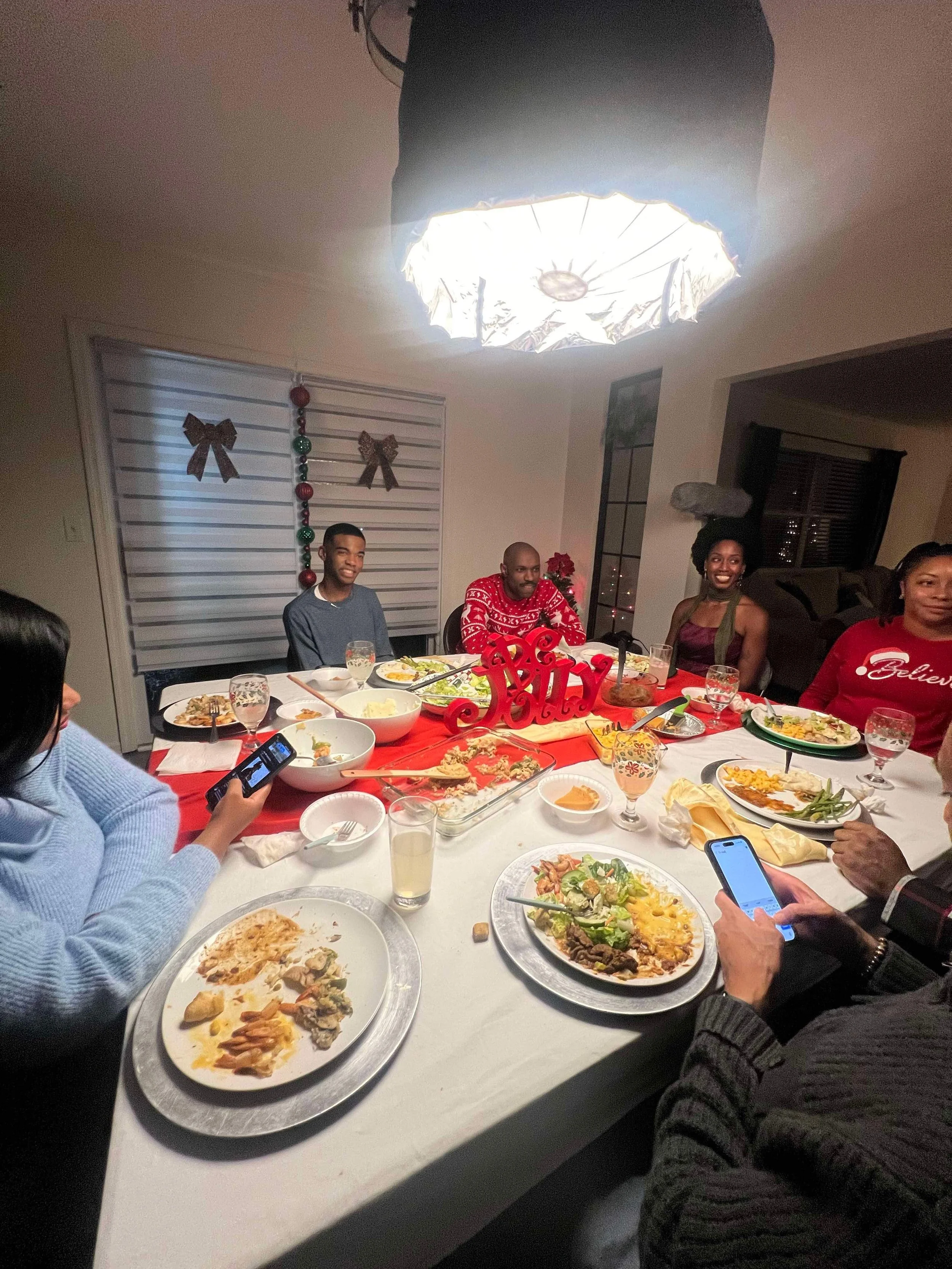 Family Christmas dinner at the dining table with food and holiday decorations.