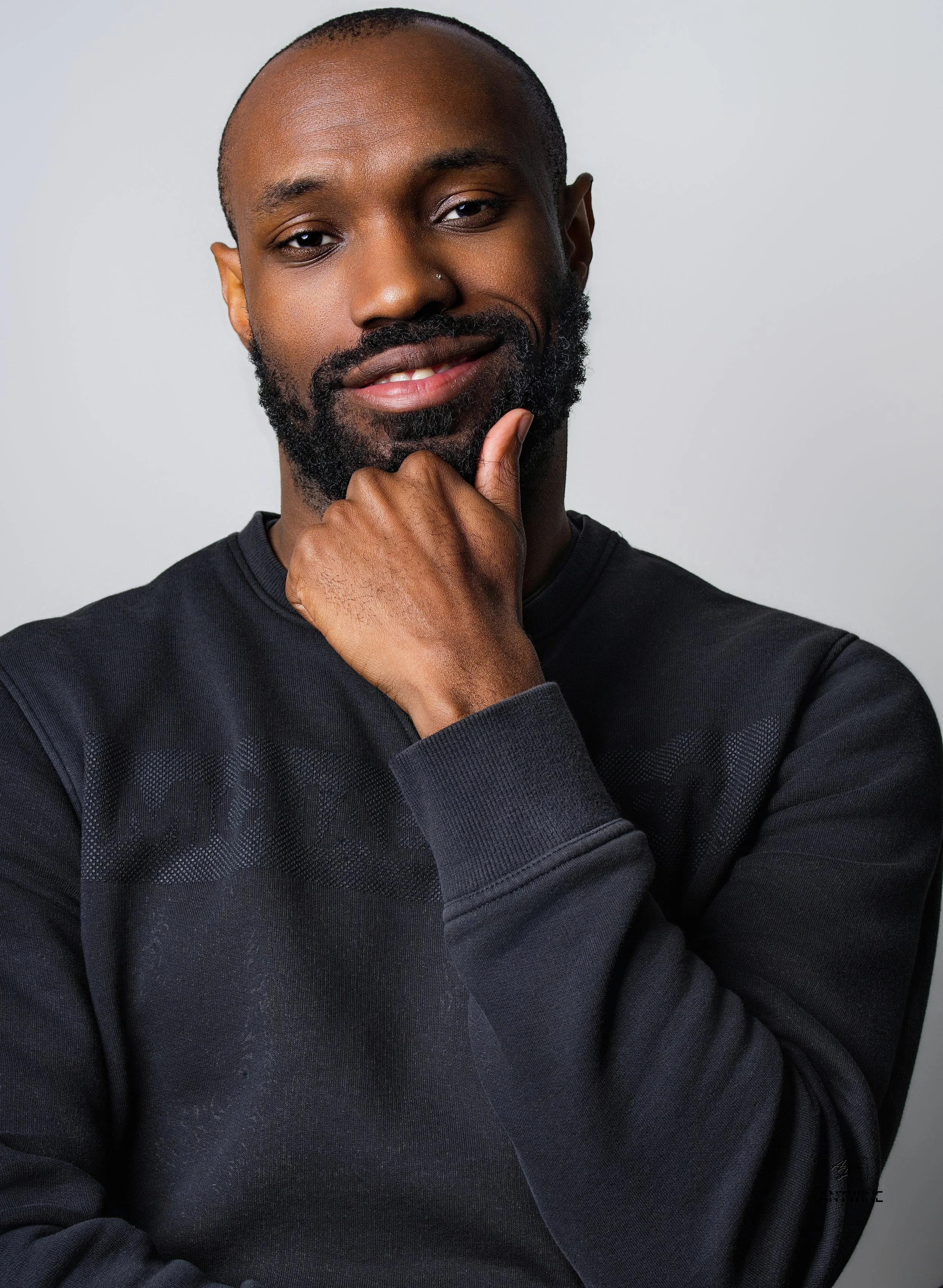 A African American male, wearing a black long sleeve shirt, smiling.