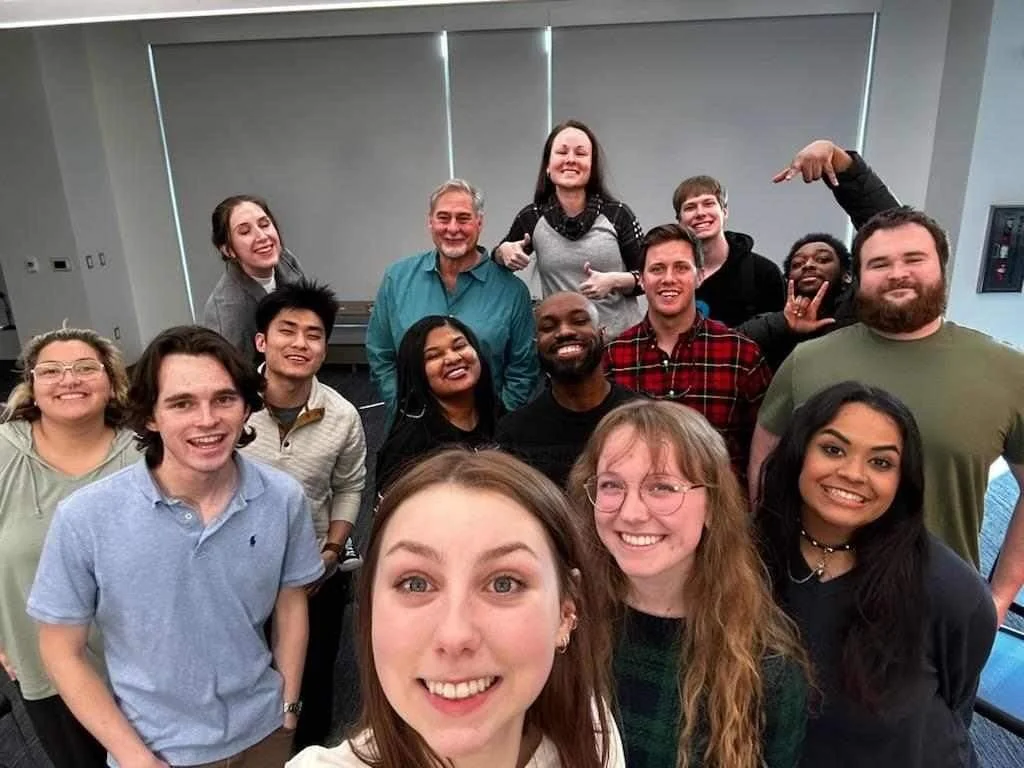 A group of diverse people smiling and posing for a group photo indoors.