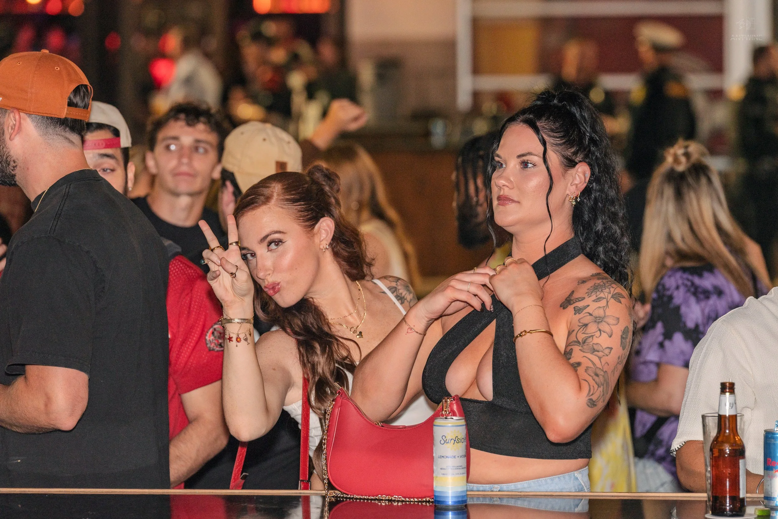 Group of young adults socializing at a bar or party, engaging in conversations and enjoying drinks.