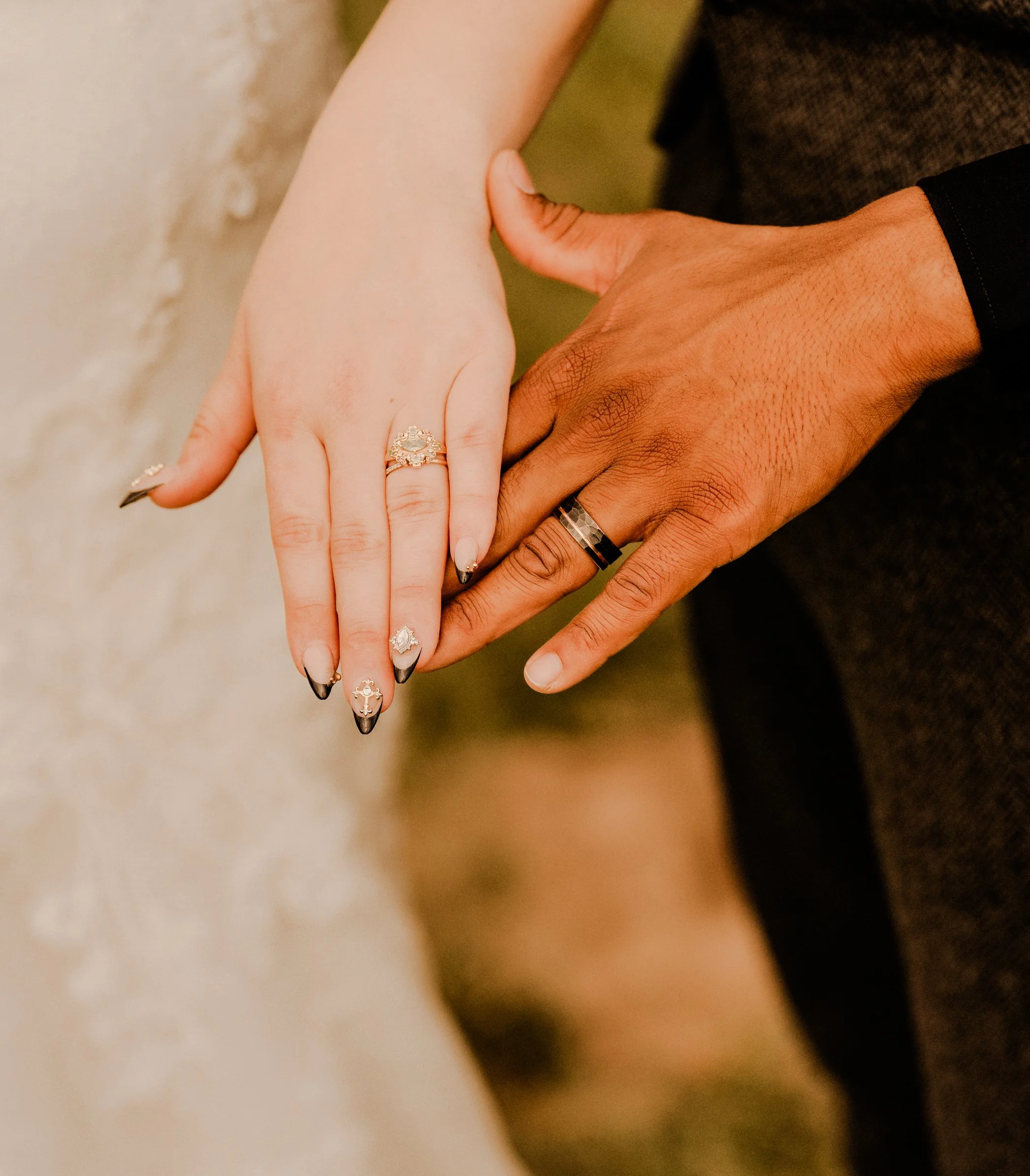Close-up of a couple's hands with wedding rings, holding each other.
