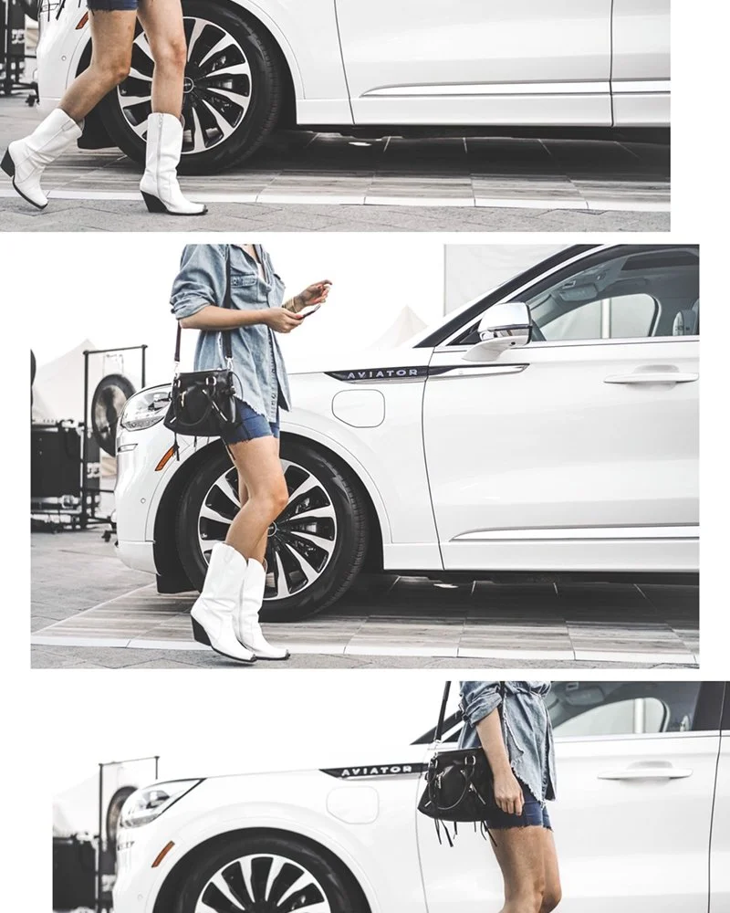 A woman in white cowboy boots, denim jacket, and shorts standing next to a white Volkswagen ID. Buzz electric vehicle at an outdoor event.