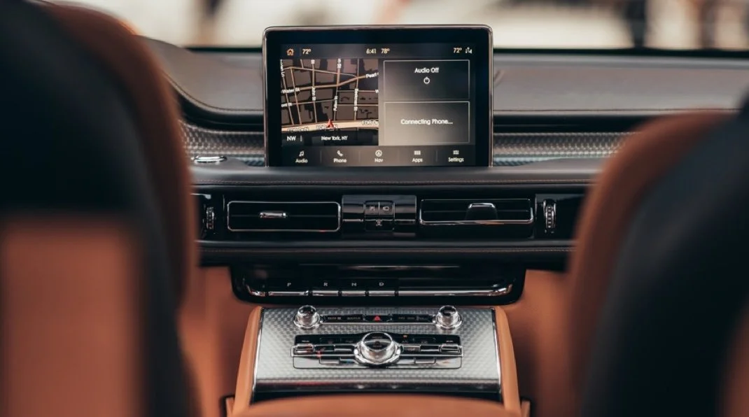 A woman in a green dress with white polka dots standing in a cityscape with tents on a rooftop during sunset, with skyscrapers in the background.