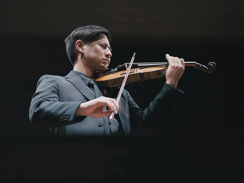 Young man in a suit playing the violin on stage