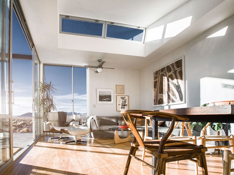 Bright living room with large windows, skylight, modern furniture, and minimal decor.