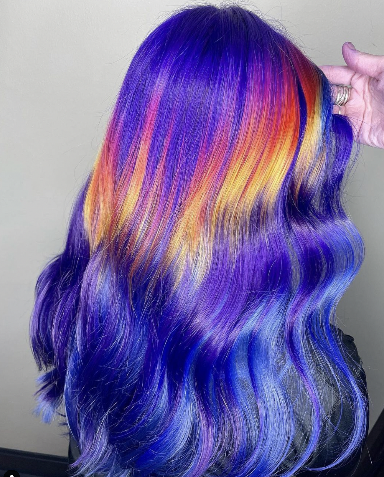 Wavy hair dyed in rainbow colors including purple, pink, orange, yellow, and blue.