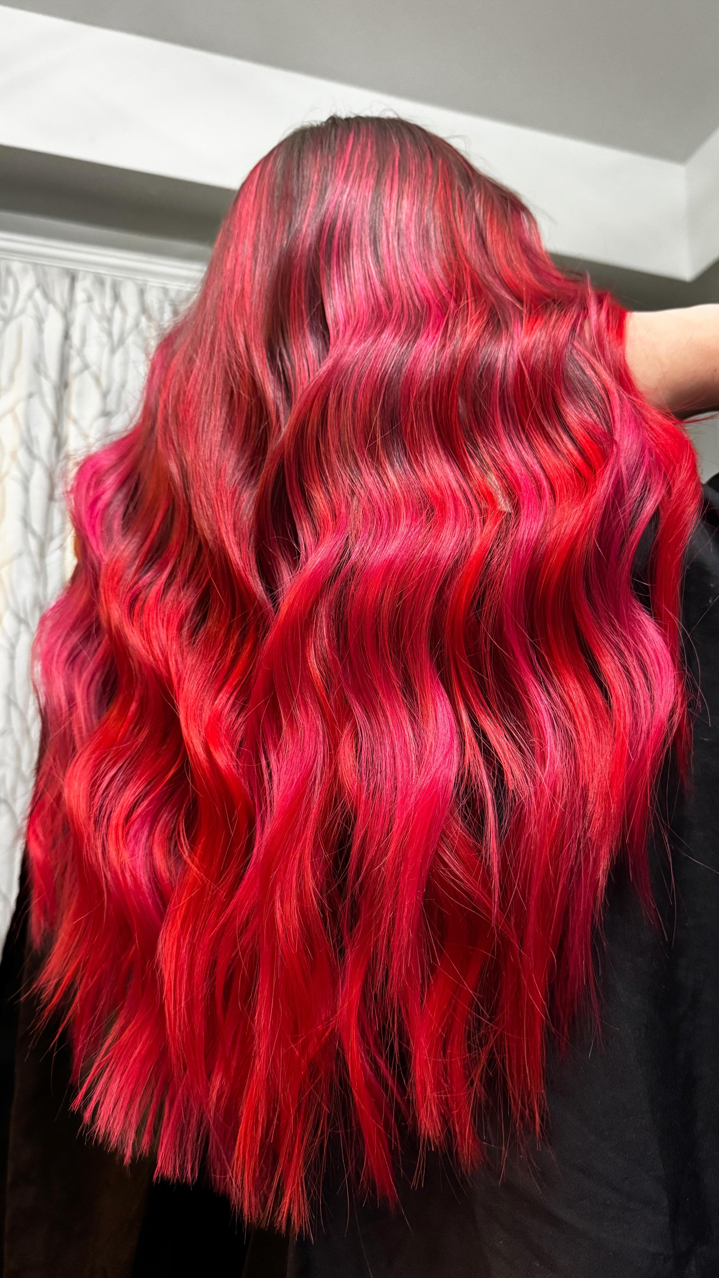 Long, wavy hair dyed in shades of red and pink.