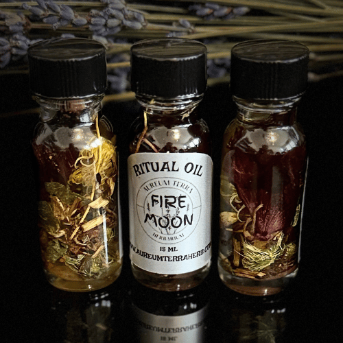 Three 15ml glass bottles of Aureum Terra Herb Fire Moon Ritual Oil containing botanicals and herbs in golden oil. Spiritual blend crafted for lunar energy, manifestation, and elemental fire magick, displayed against a lavender background.