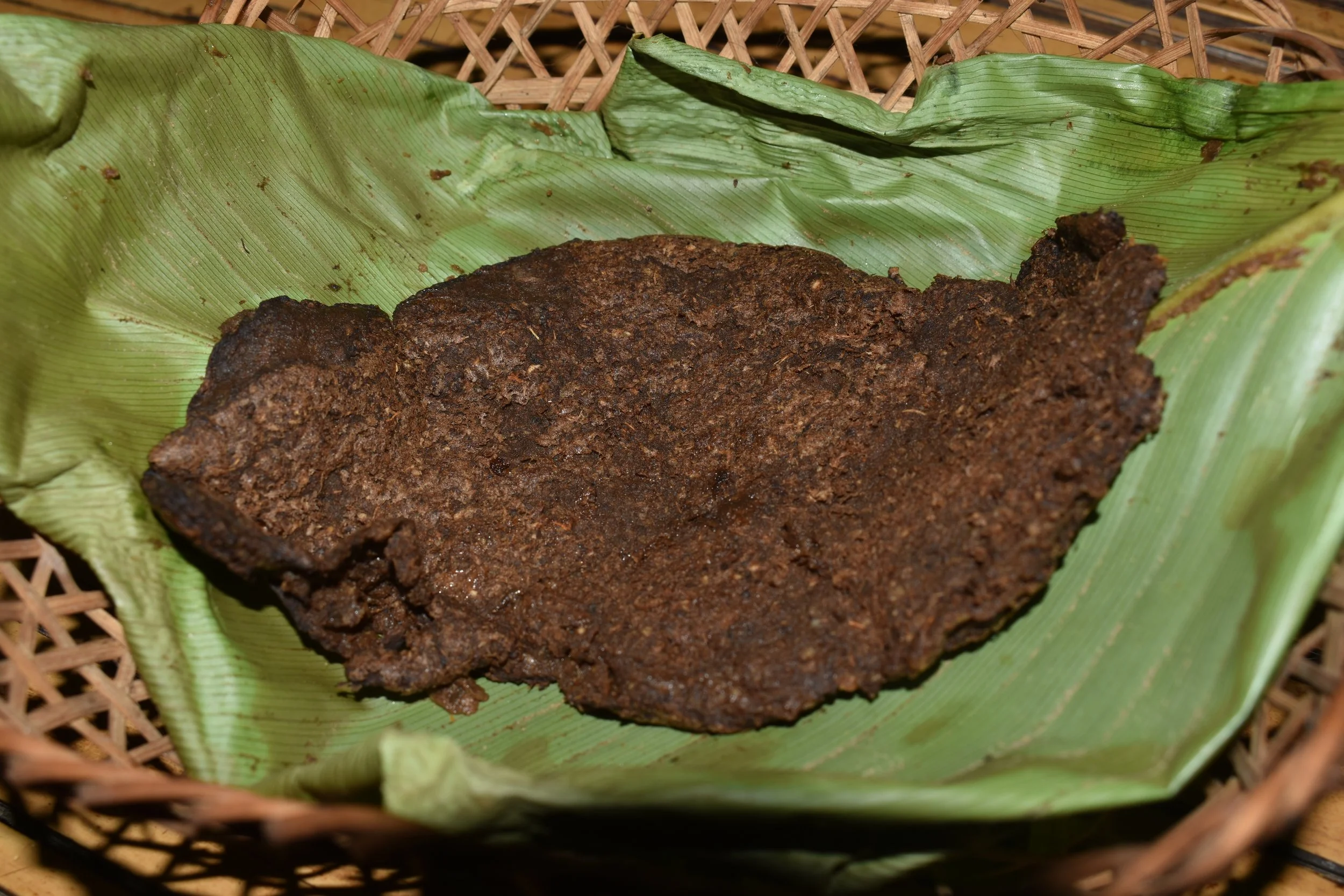 The Atheeh Naphu (fermented tree fern chapati) is elegantly arranged in a traditional Naphu-Sichey (where Naphu means roti/chapati and Sichey refers to a leaf) placed in a small, traditionally woven basket, ready to be served or eaten. Both the leaf 