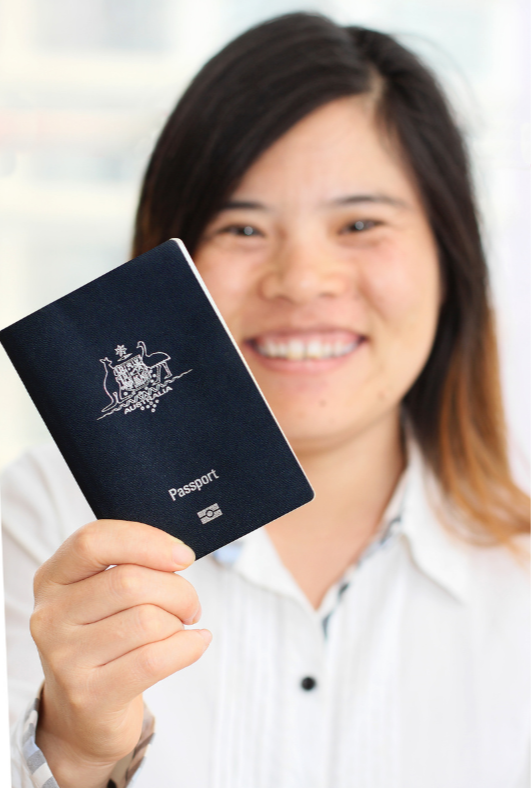 Woman smiling and holding an Australian passport in front of her.