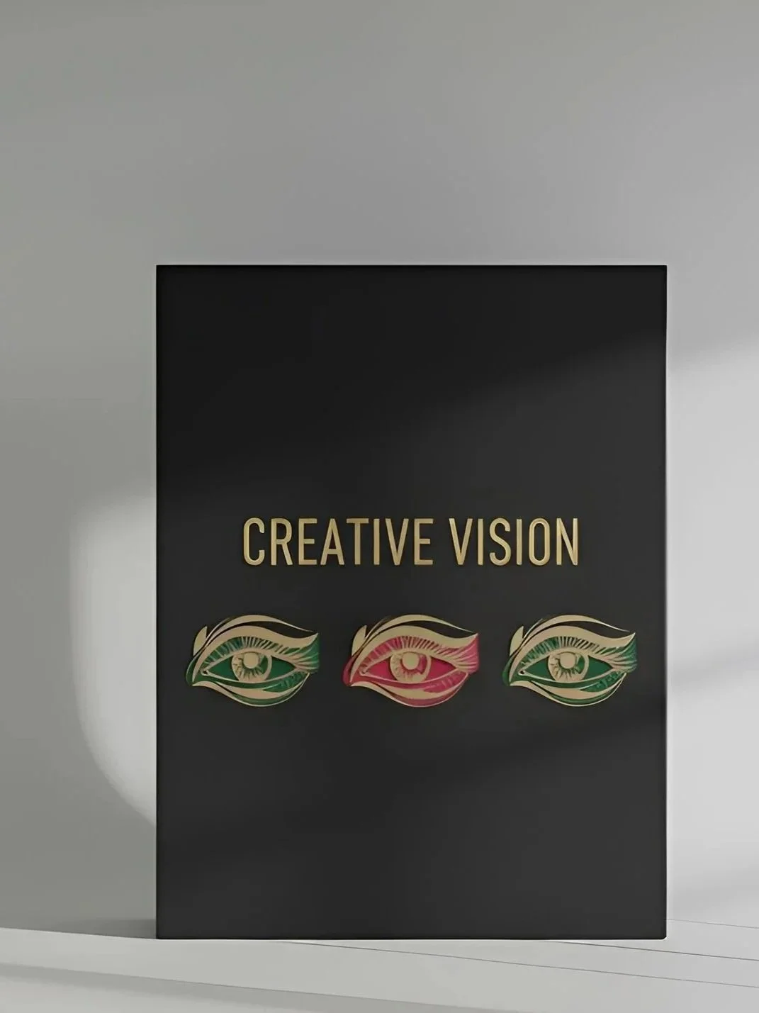 A black box with gold text that says "CREATIVE VISION" and three stylized eye illustrations, each with differently colored eyelashes and irises in green and red.