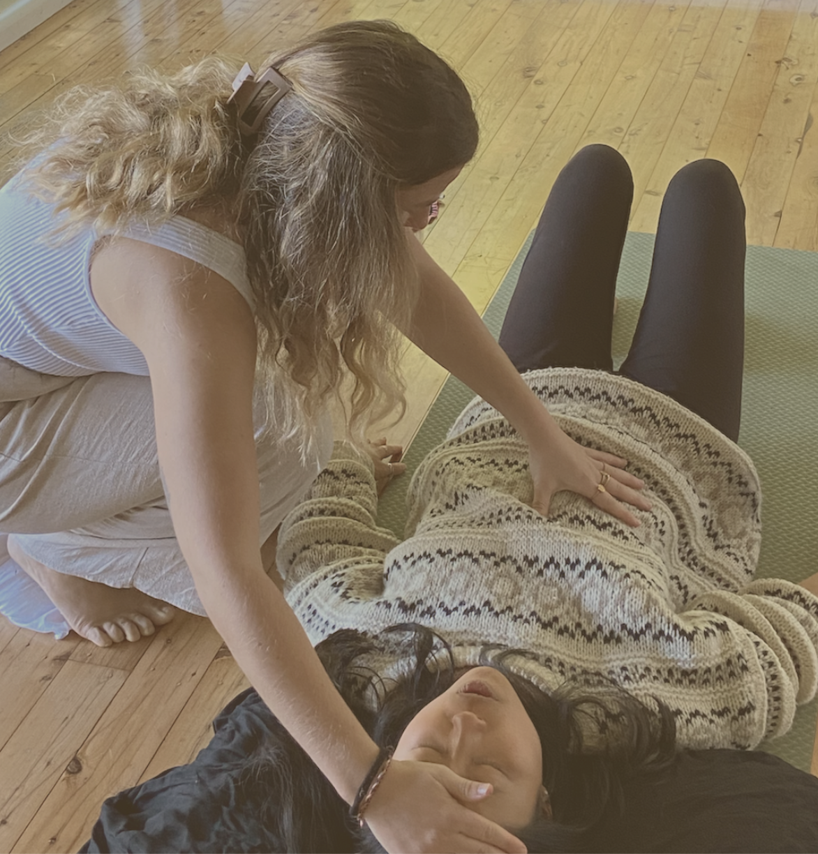 A woman receiving a chiropractic adjustment from another woman lying on a massage table.