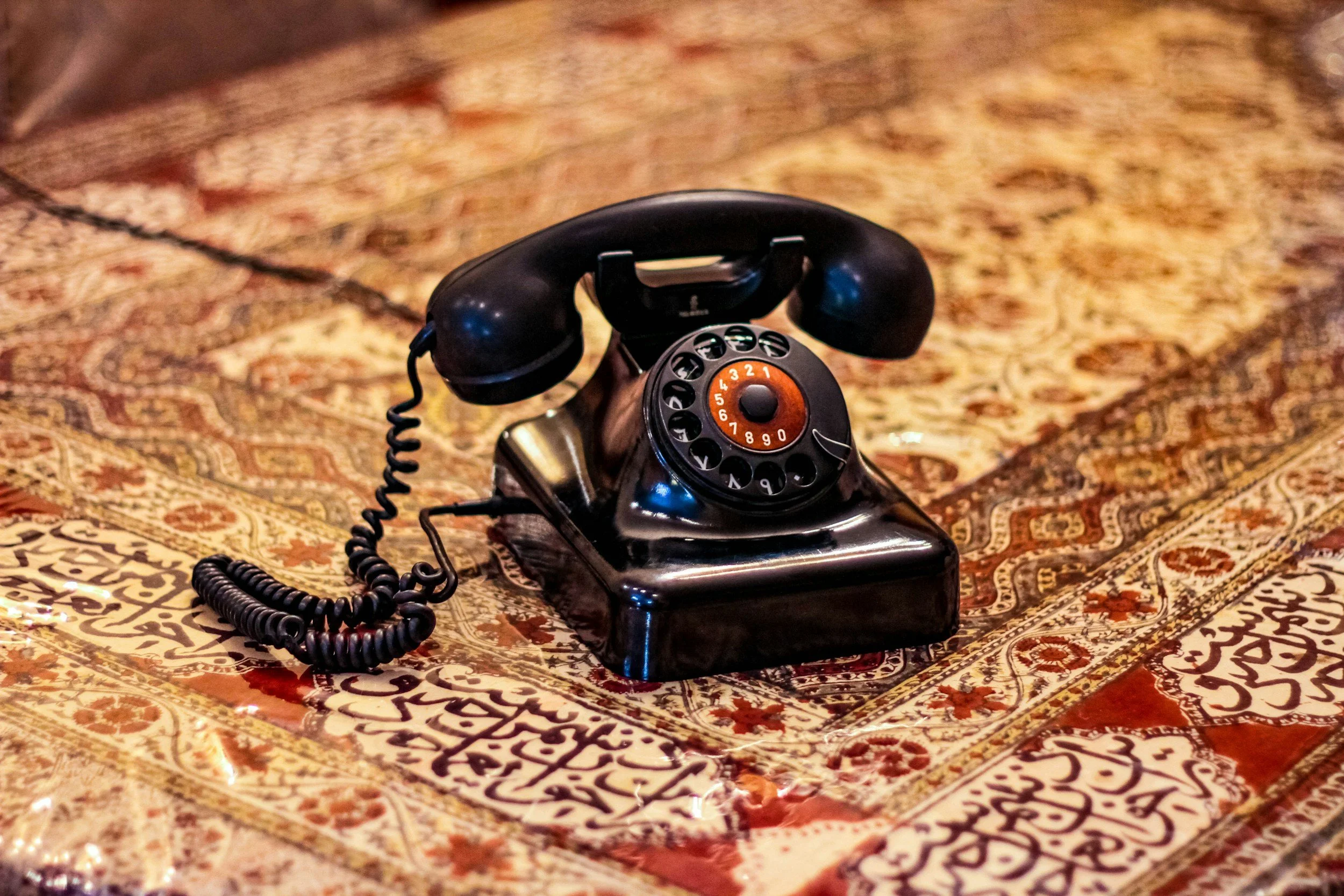 Teléfono antiguo negro en una alfombra decorativa.