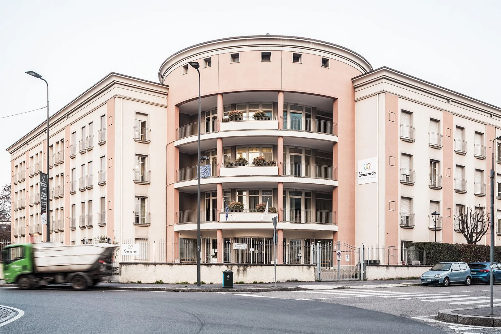 Edificio residenziale a più piani con balconi circolari, pareti di colore rosa e bianco, in una zona urbana.