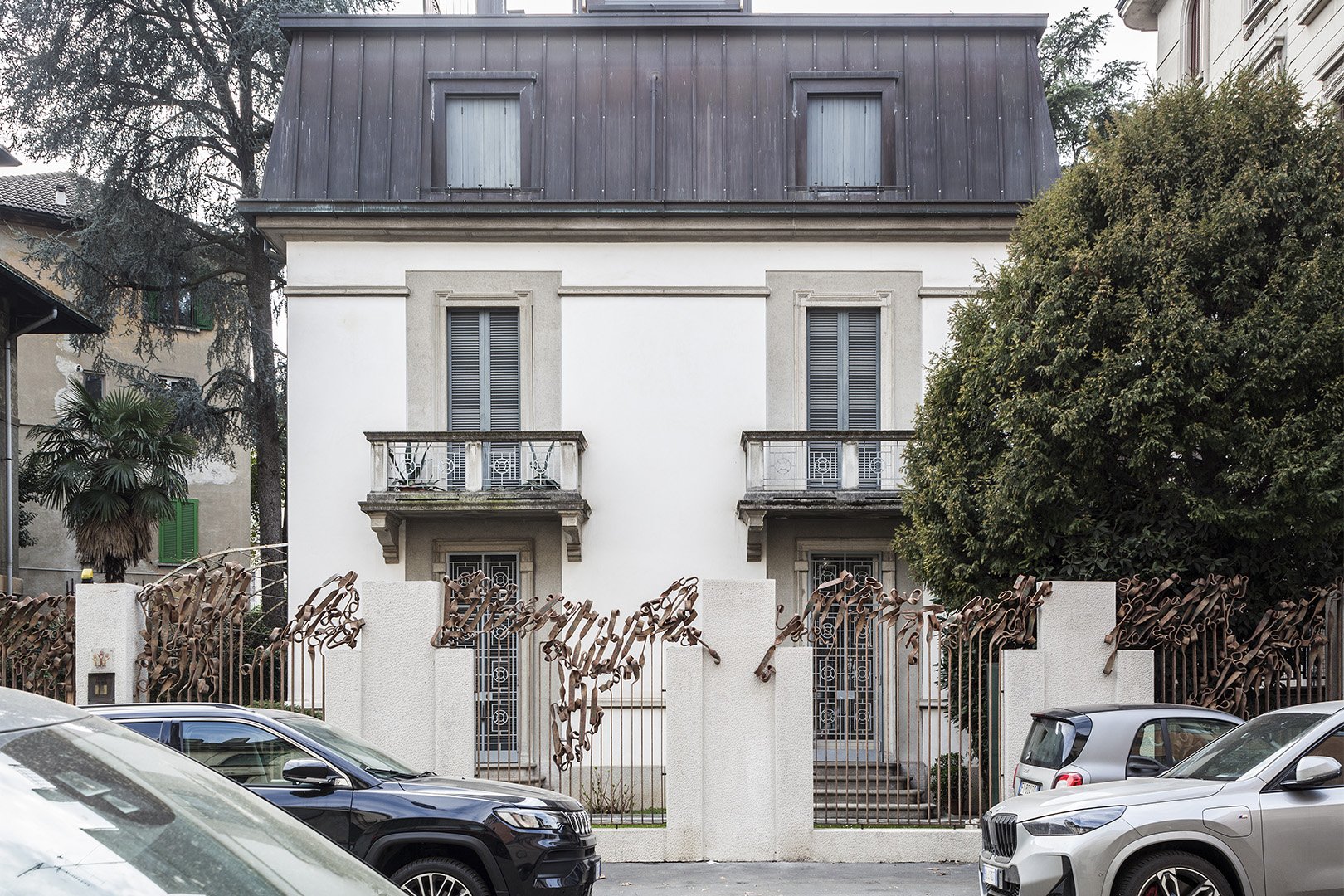 Casa di quattro piani con mura bianche, finestre con grate metalliche e balconi. La recinzione è decorata con forme di chiavi di metallo.