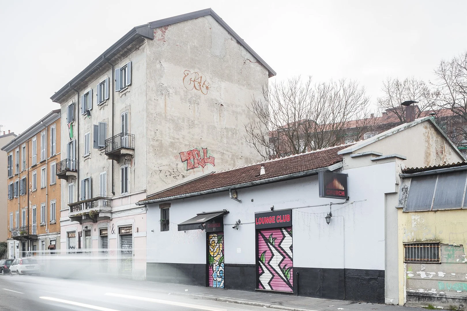 Edificio con affaccio su strada, con mural e graffiti, e un locale aperto chiamato 'Lounge Club'.