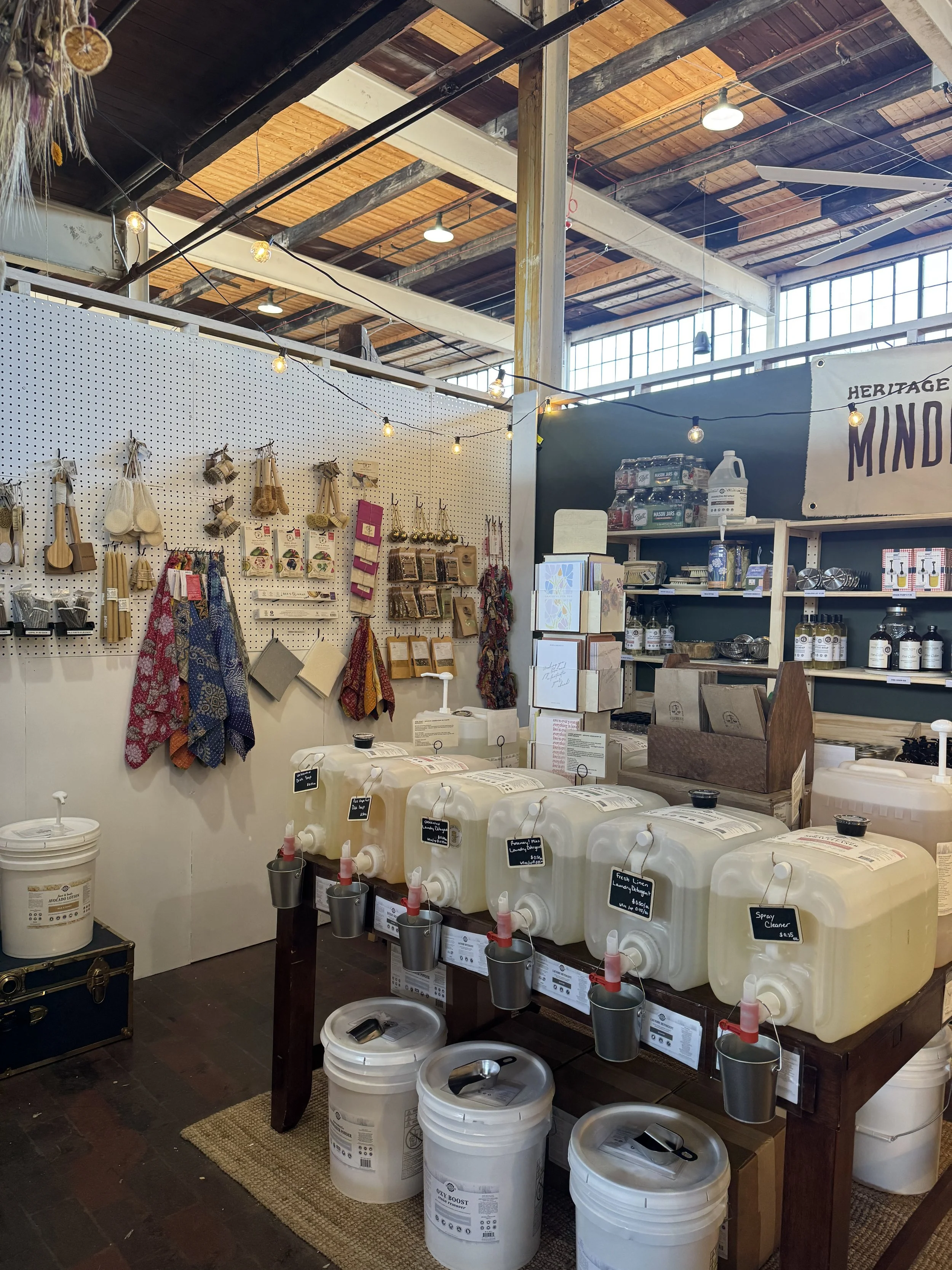 Kitchen countertop with glass jars holding tea-making tools, a metal container with a handle, and utensils in a metal holder, set against a brick wall background.