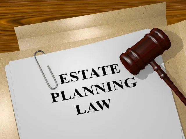 A gavel resting on a paper that reads 'Estate Planning Law', with a paperclip attaching the paper to some documents.