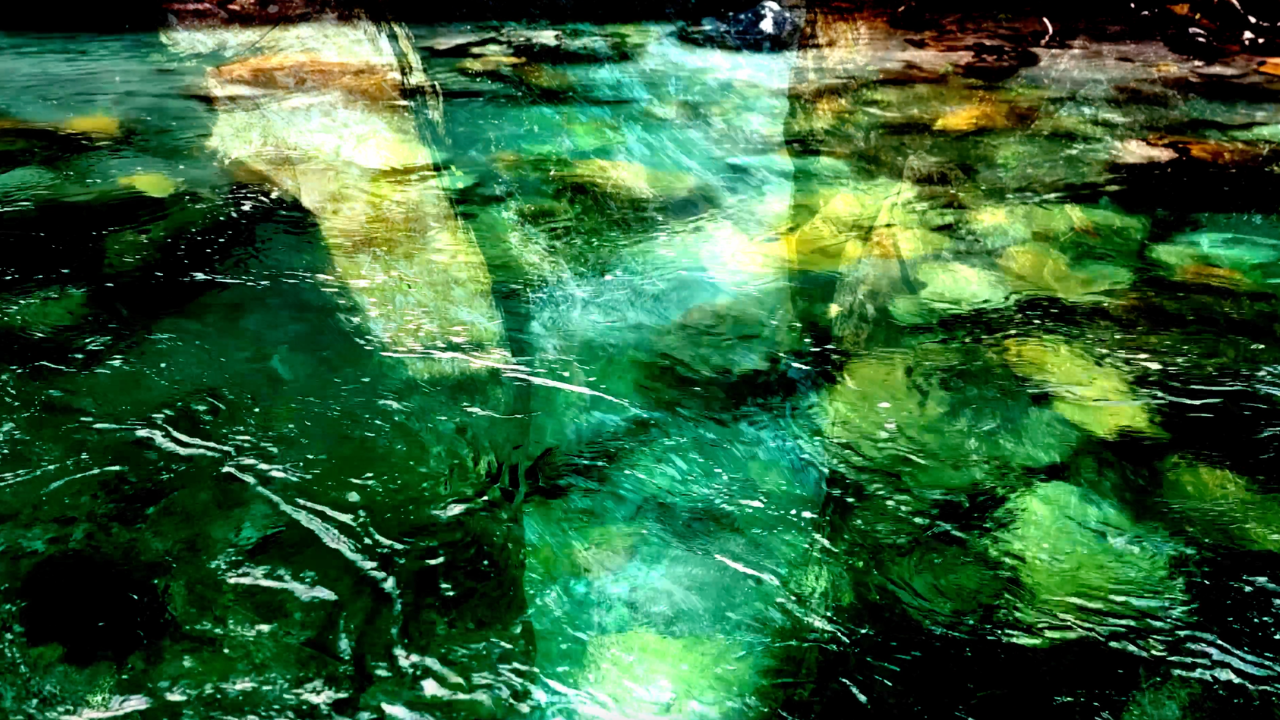 Multicolored abstract water with green, yellow, and black hues, with ripples and reflections.