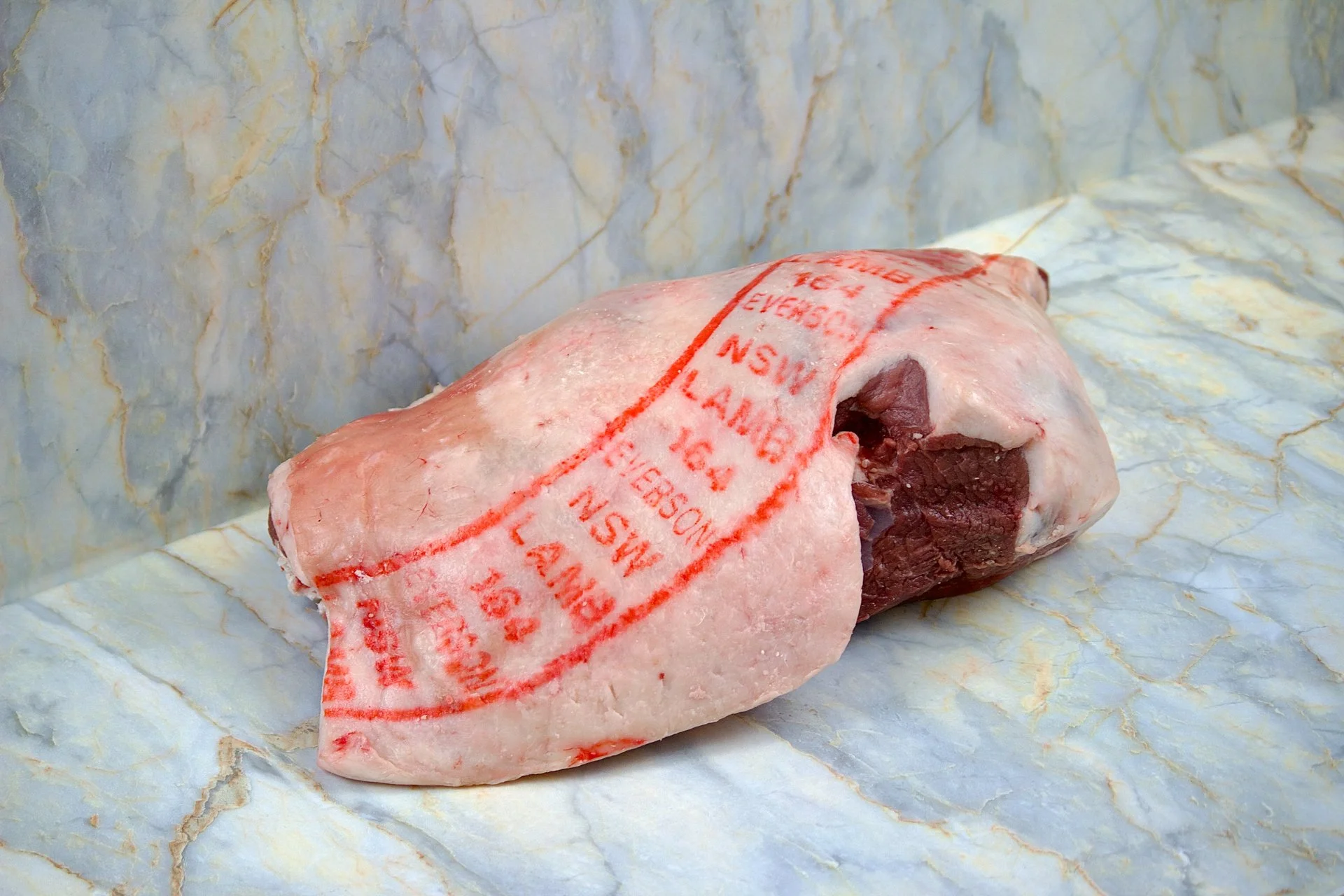 Raw beef tenderloin wrapped in butcher's paper on a marble surface.