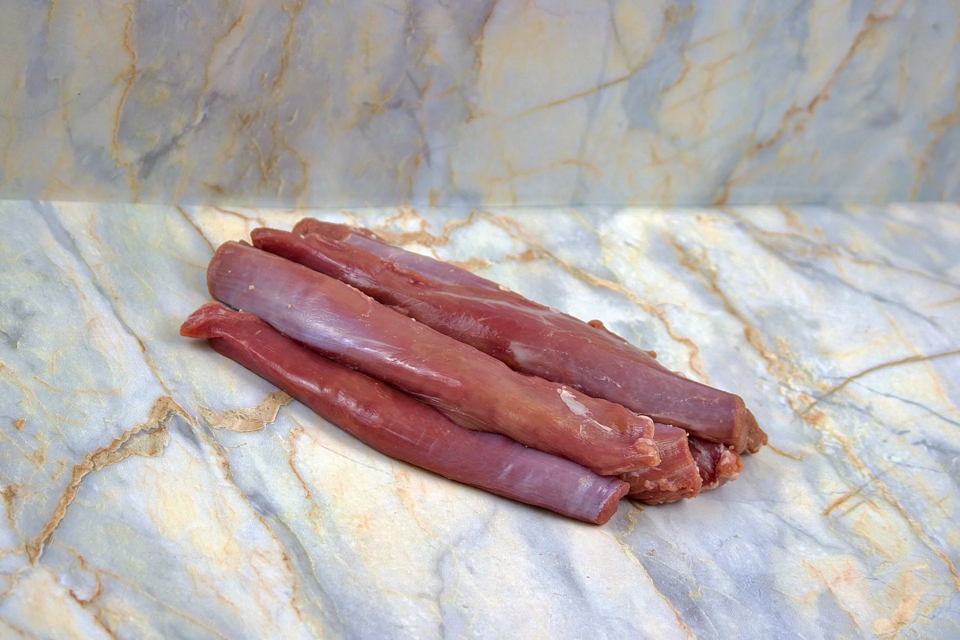 Raw elk meat placed on marble paper, ready for cooking or processing.