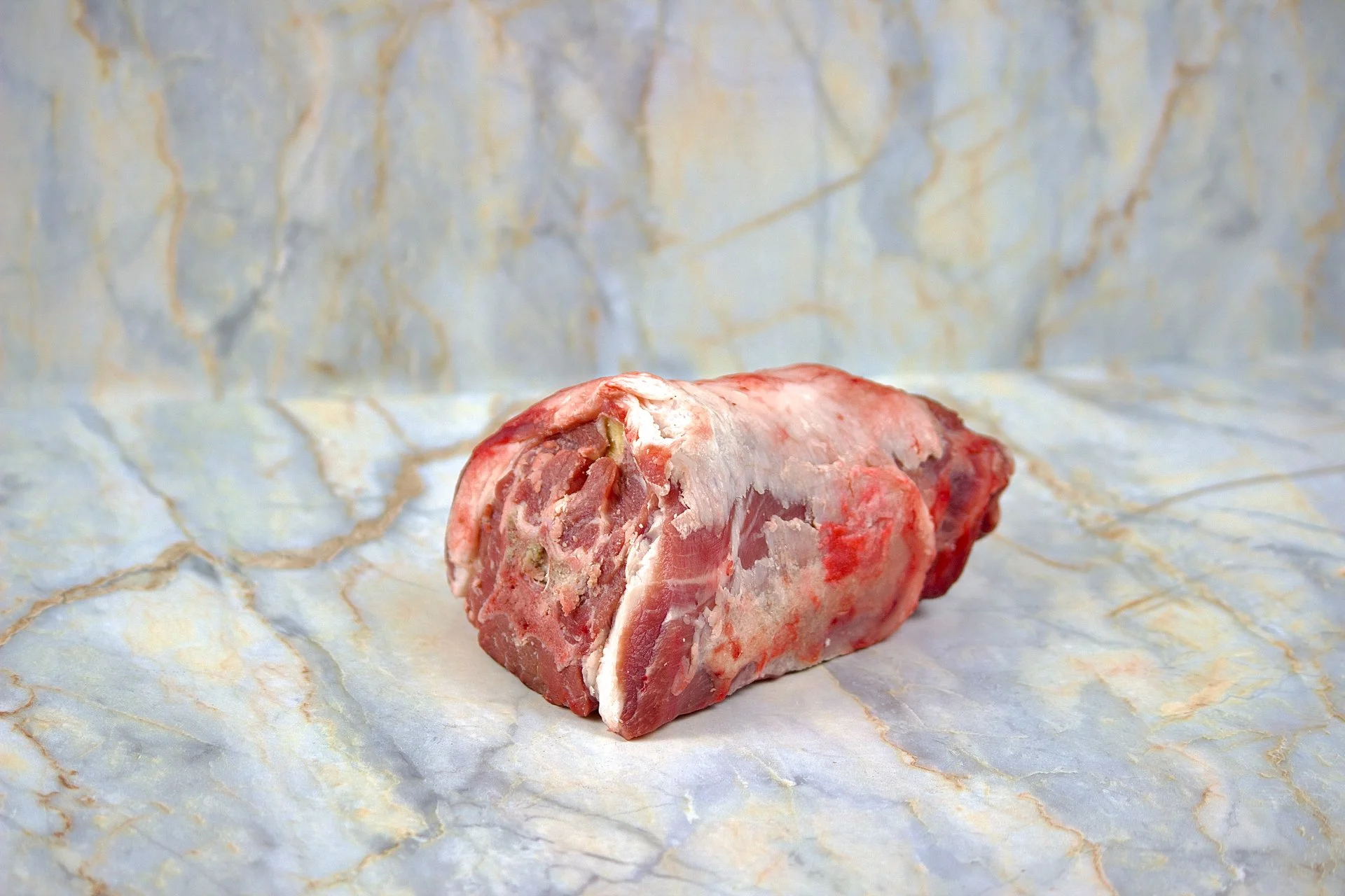 Raw beef marrow bone on marble surface.