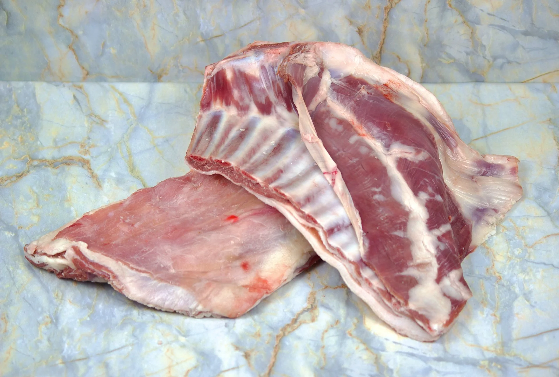 Raw meat cuts on marble surface.