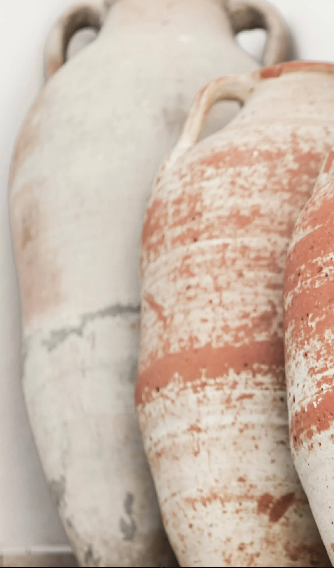 Close-up of three ancient pottery vessels with weathered surfaces, arranged side by side.