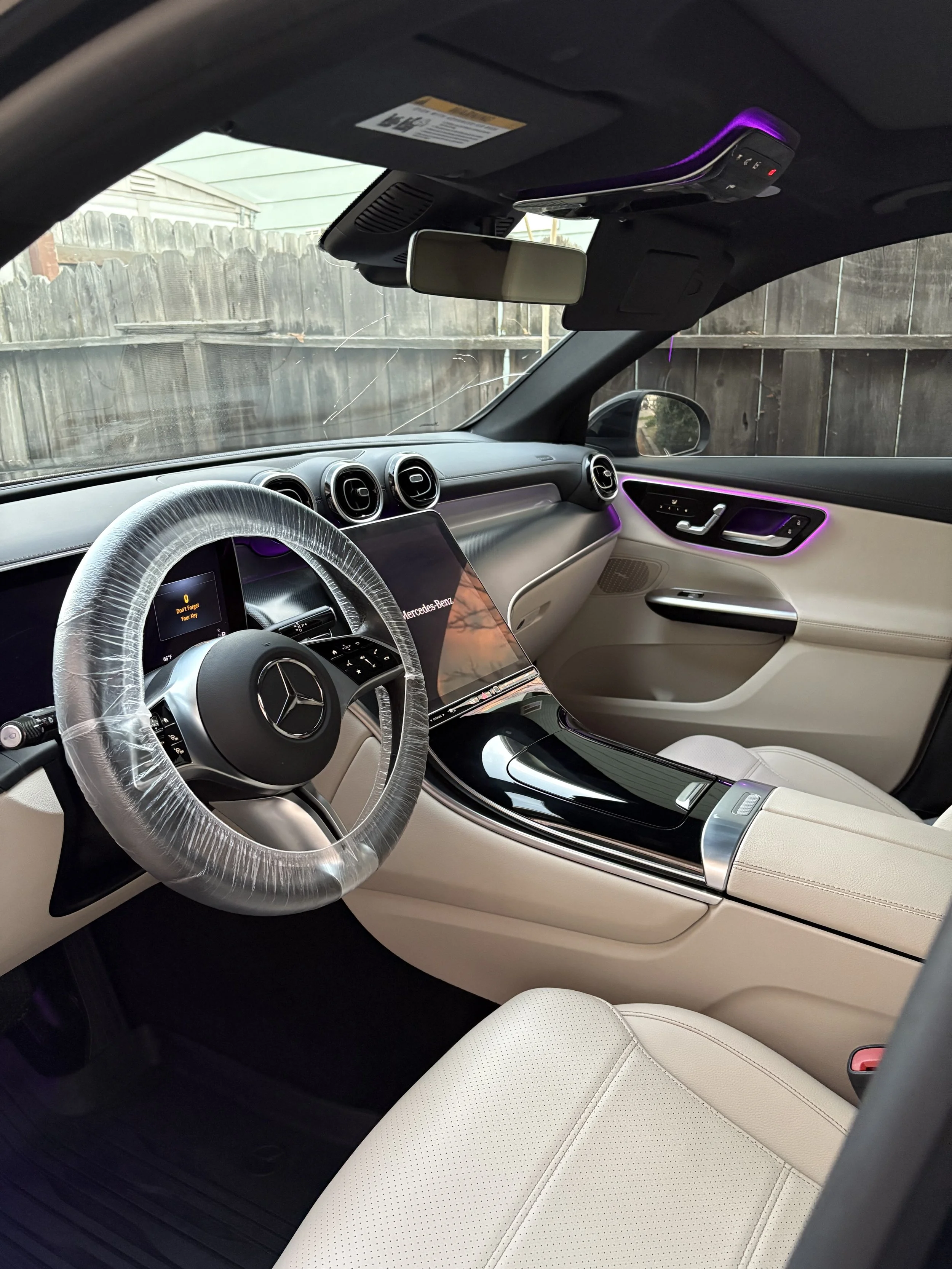 Interior of a Mercedes-Benz detailed by Fastlane Detailing in Atascadero, CA—showing beige leather seats, digital displays, and purple LED accent lighting.