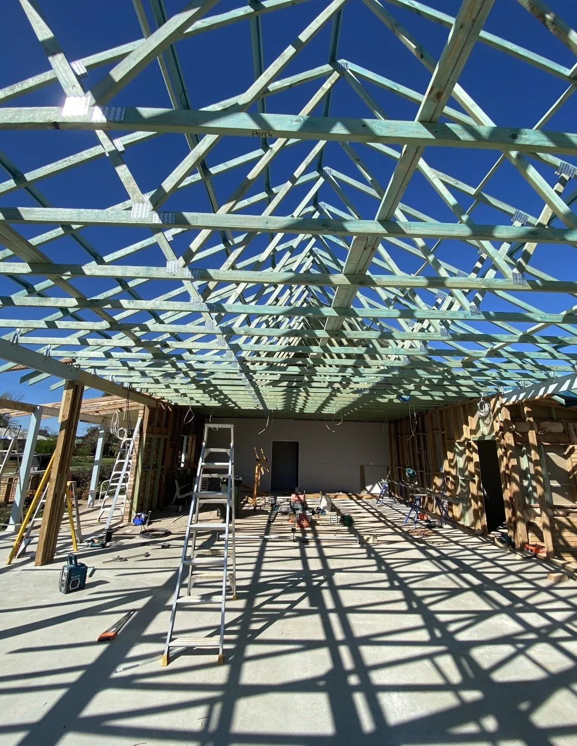 Construction site showing the wooden roof framework being built inside a house under construction.