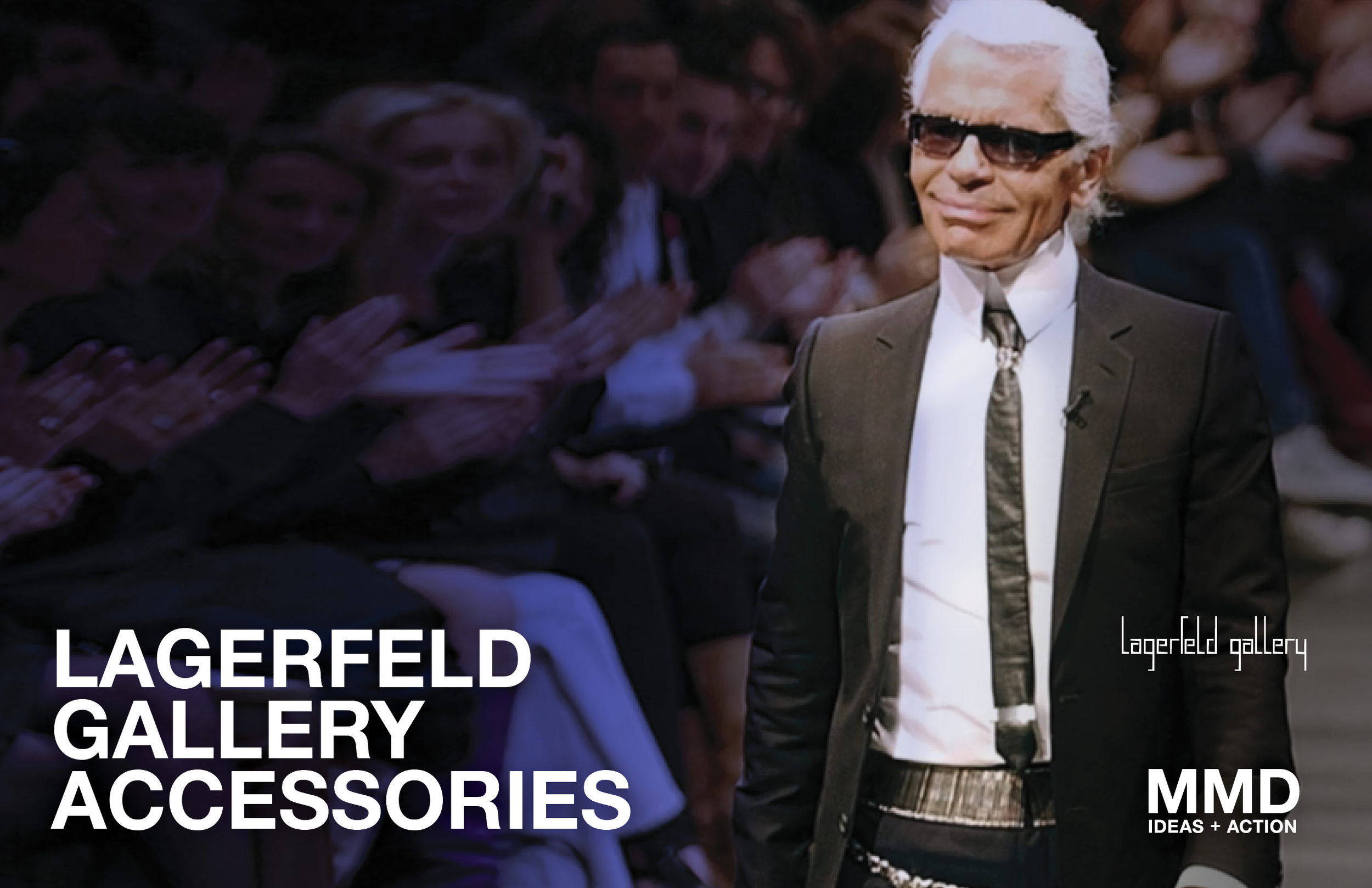 A man with white hair, sunglasses, and a black suit walking on a runway at a fashion show, with an audience clapping in the background.