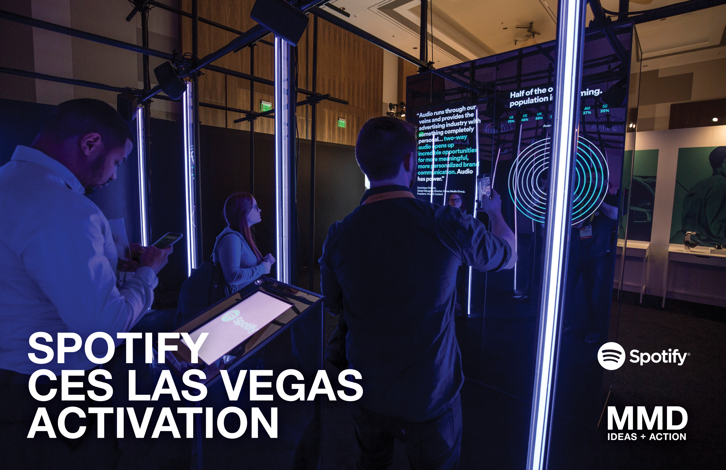 People at Spotify booth during CES in Las Vegas, engaging with digital displays and screens.