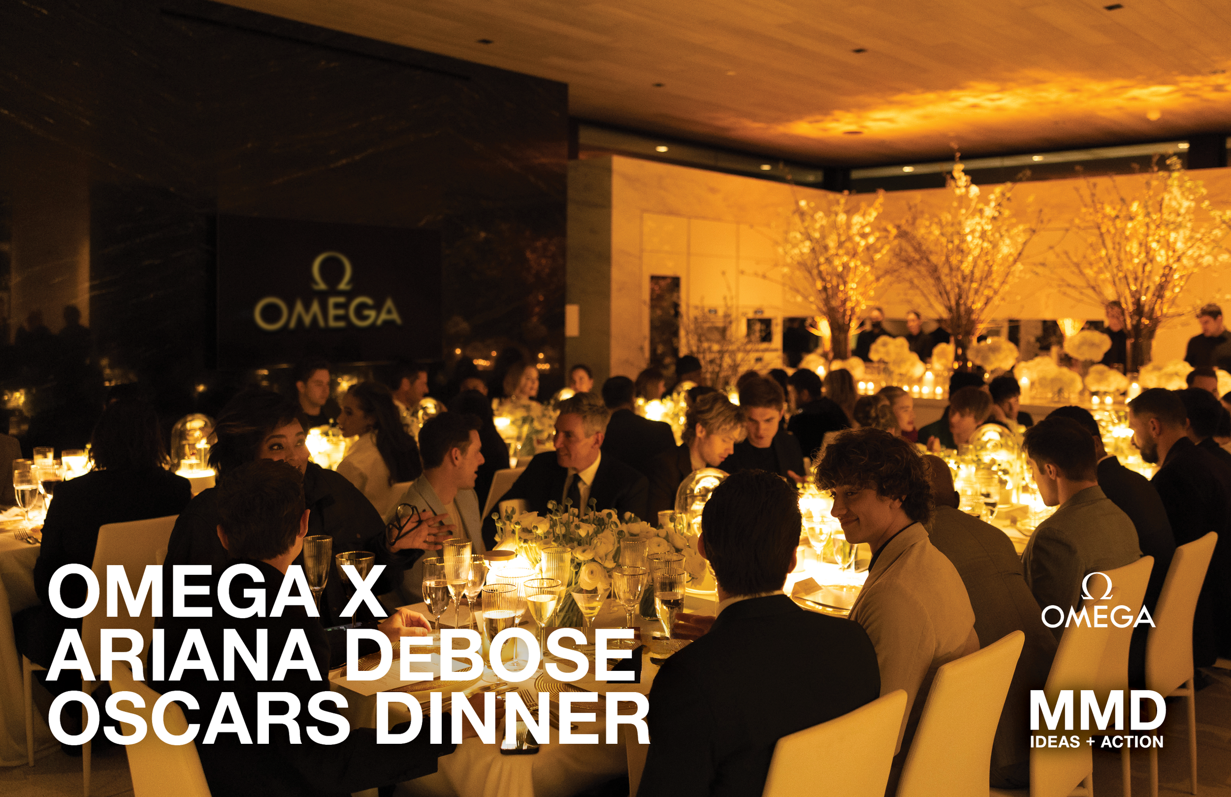 People seated at a formal dinner table with floral centerpieces and candles, attending Omega x Ariana DeBose Oscars dinner event.
