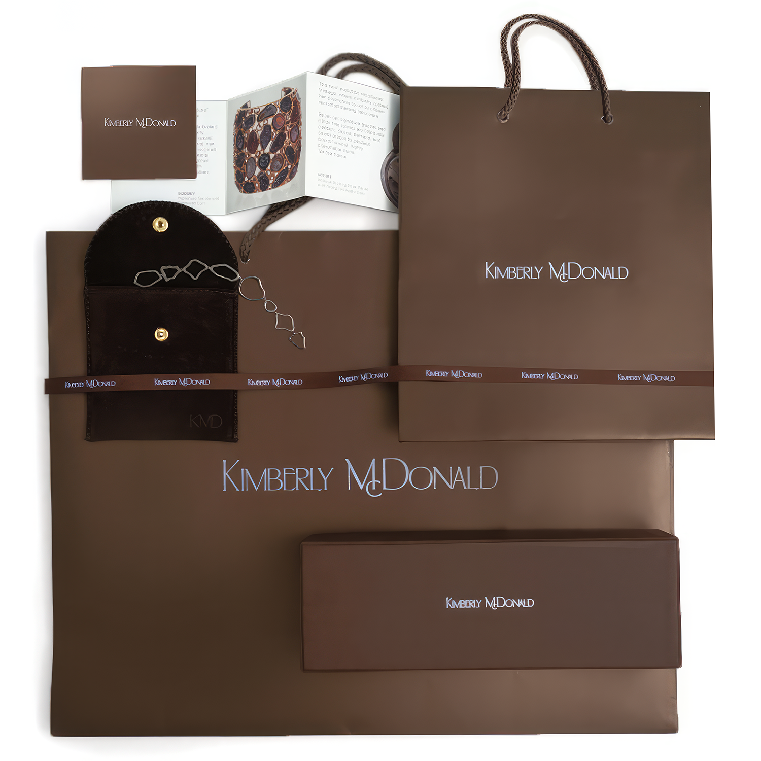 Kimberly McDonald branded shopping bag, jewelry box, and informational booklet, all in brown.