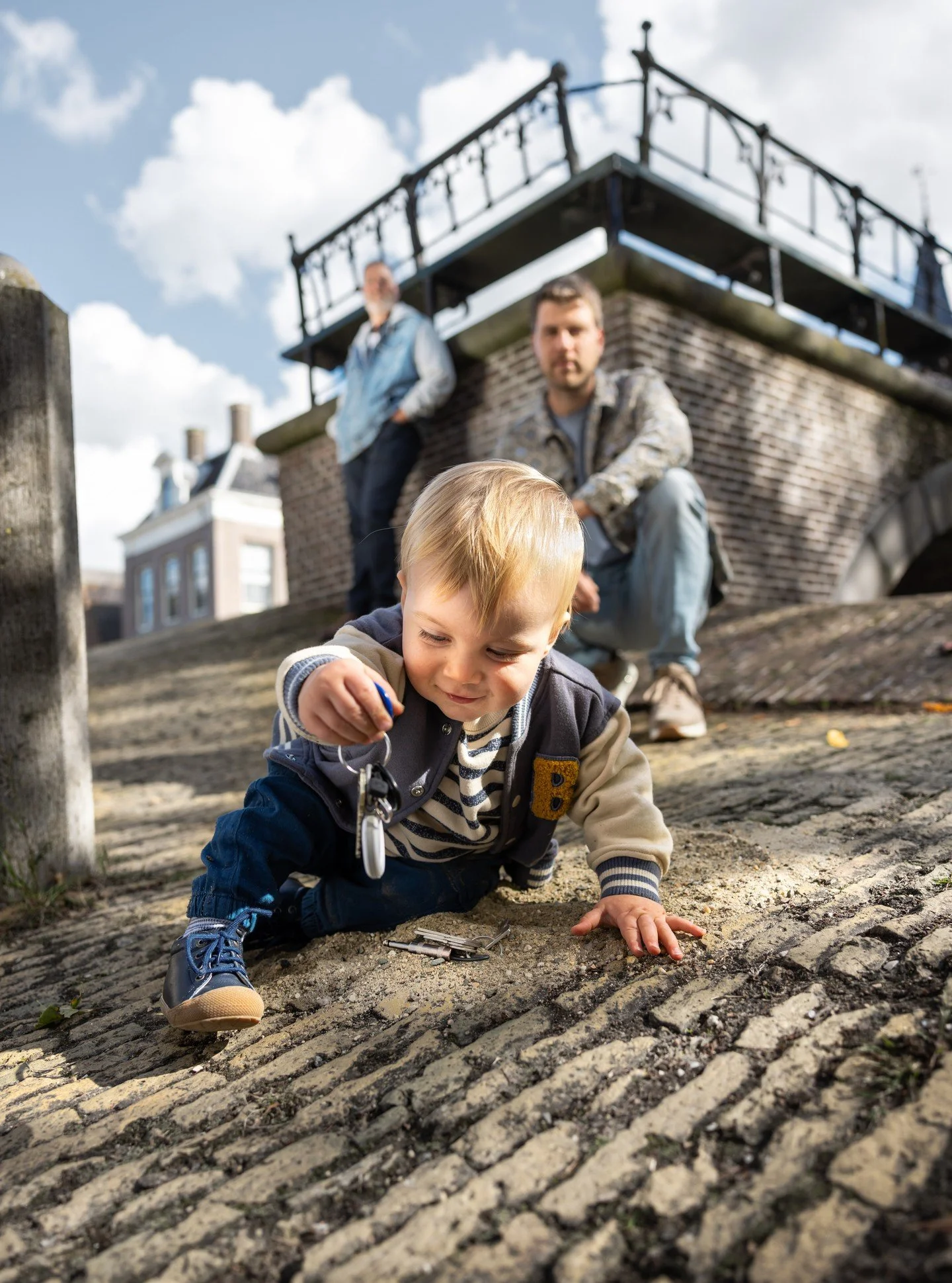 Mijn eerste expositiefoto met mijn grote vriend Joes, zijn papa Jim en opa Peter:

𝗗𝗿𝗶𝗲 𝗴𝗲𝗻𝗲𝗿𝗮𝘁𝗶𝗲𝘀 𝗶𝗻 𝗲𝗲𝗻 𝗯𝗲𝗲𝗹𝗱. Het kind scherp, symbool voor de toekomst, spelend met zand en sleutels. Het zand verwijst naar sterrenstof: waar