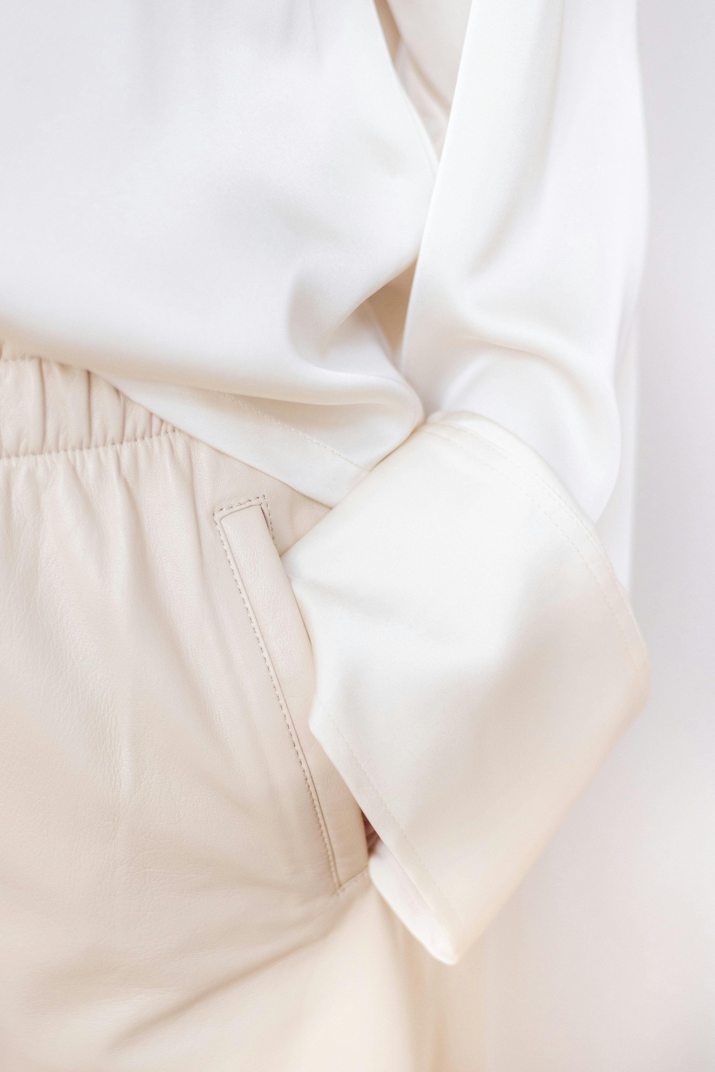 Vêtements en tissu blanc, incluant un haut en satin et un pantalon en cuir ou faux cuir.