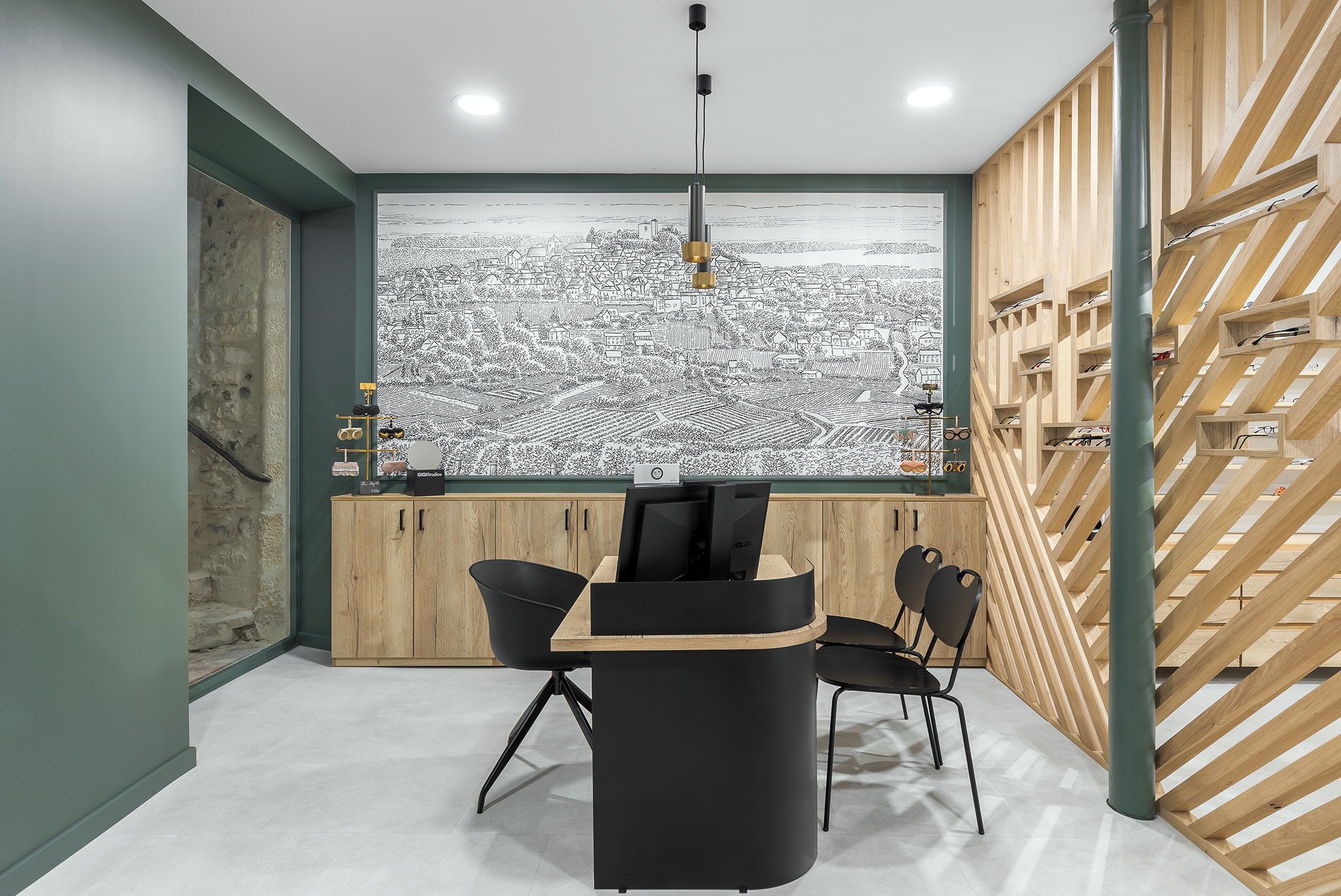 Salle de consultation ou de réception dans un bureau moderne avec un mur en arrière-plan représentant un paysage urbain en dessin. Mobilier en bois, ordinateur, chaises noires, étagères à lunettes de vue, et une décoration élégante avec une ambiance
