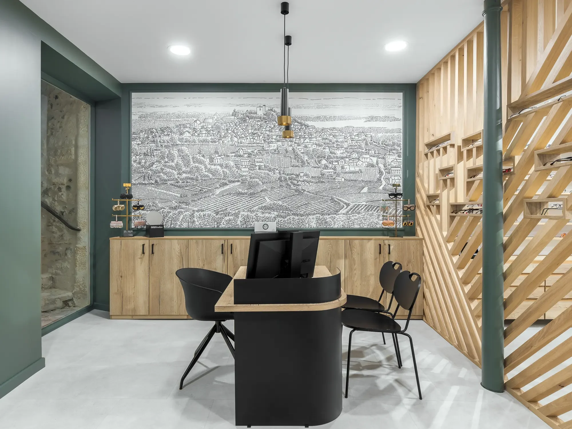 Bureau moderne avec mur en bois, peinture verte, grande fresque noir et blanc d'une ville en arrière-plan, mobilier en bois et noir, avec deux chaises et un bureau avec deux moniteurs.