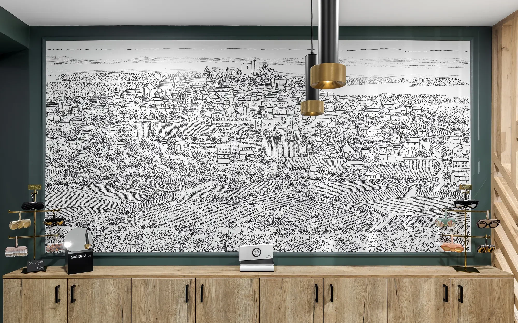 Mur illustrant un paysage urbain et rural en noir et blanc dans un magasin, avec des étagères à lunettes en métal doré sur le devant.